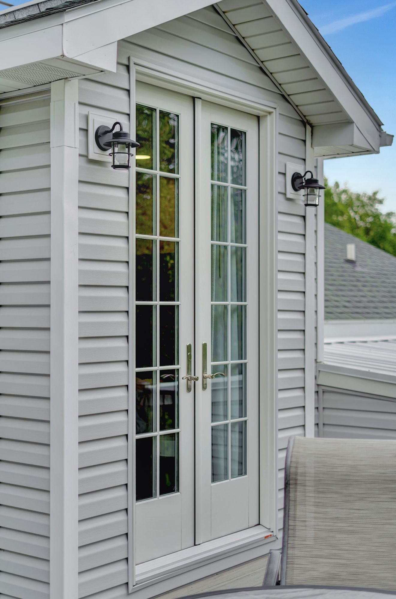 A white house with a patio door and a chair in front of it.