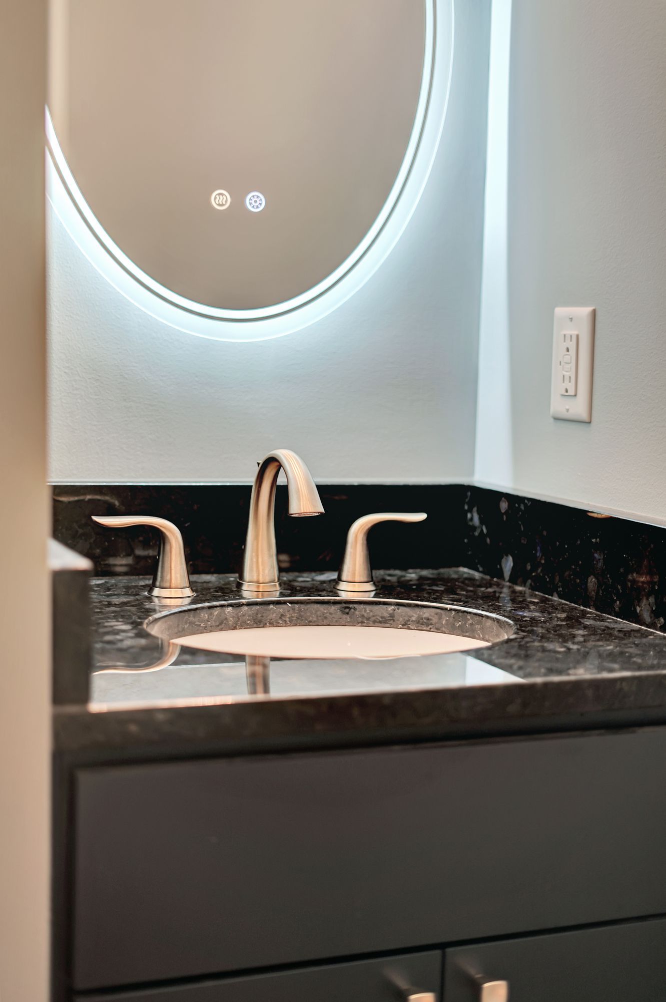 A bathroom sink with a round mirror above it.