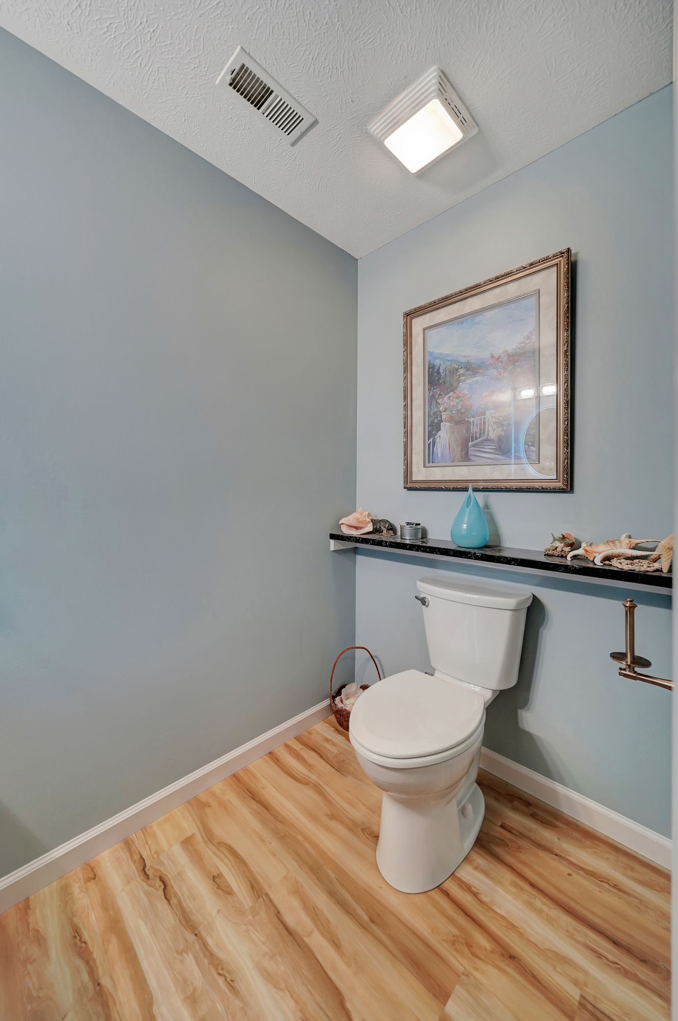 A bathroom with a toilet and a picture on the wall.