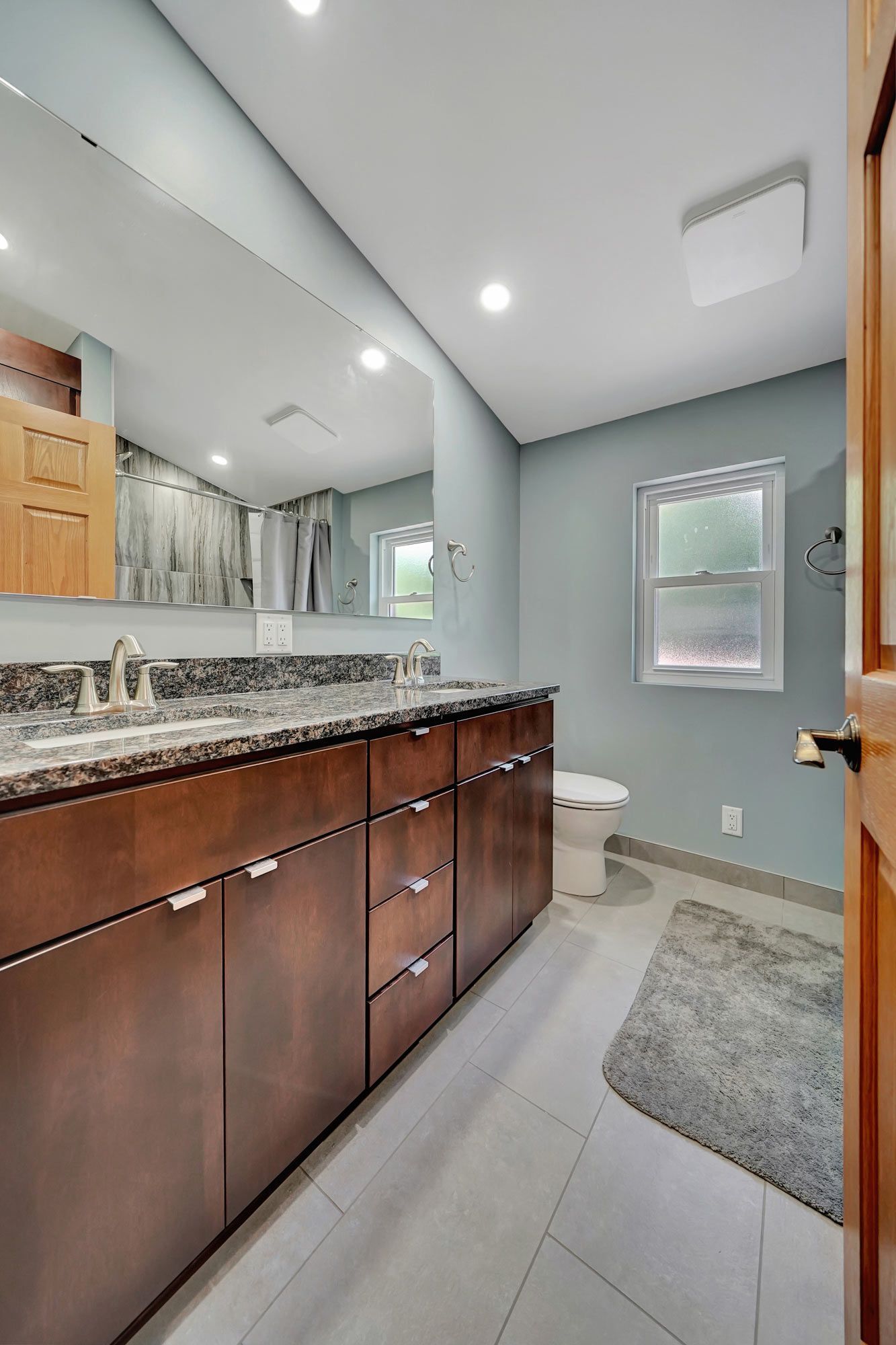 Bathroom With Two Sinks , A Toilet , And A Large Mirror | Lincoln, NE | SkyLimit Remodeling
