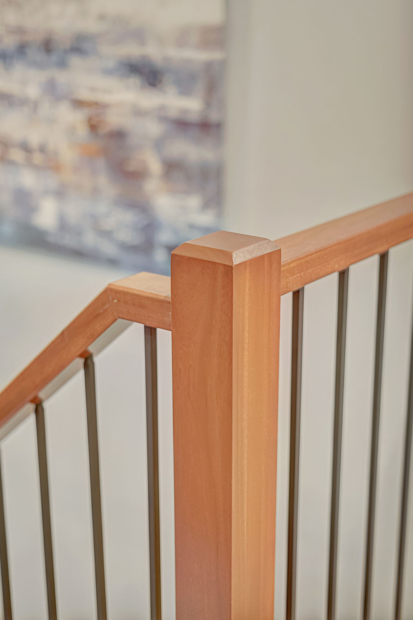 Wooden staircase railing with dark metal vertical bars.