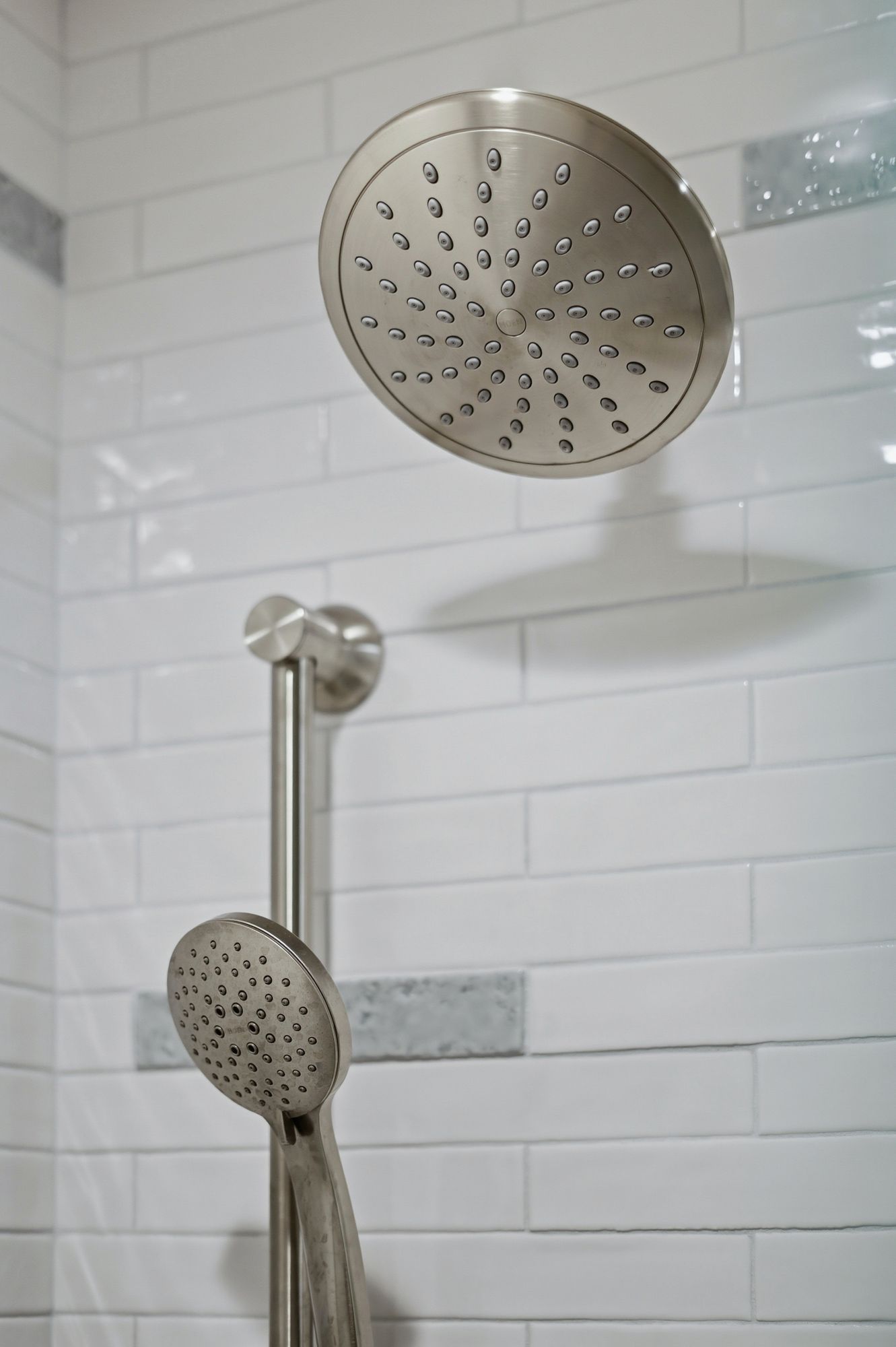 Chrome showerhead and handheld shower in a tiled bathroom