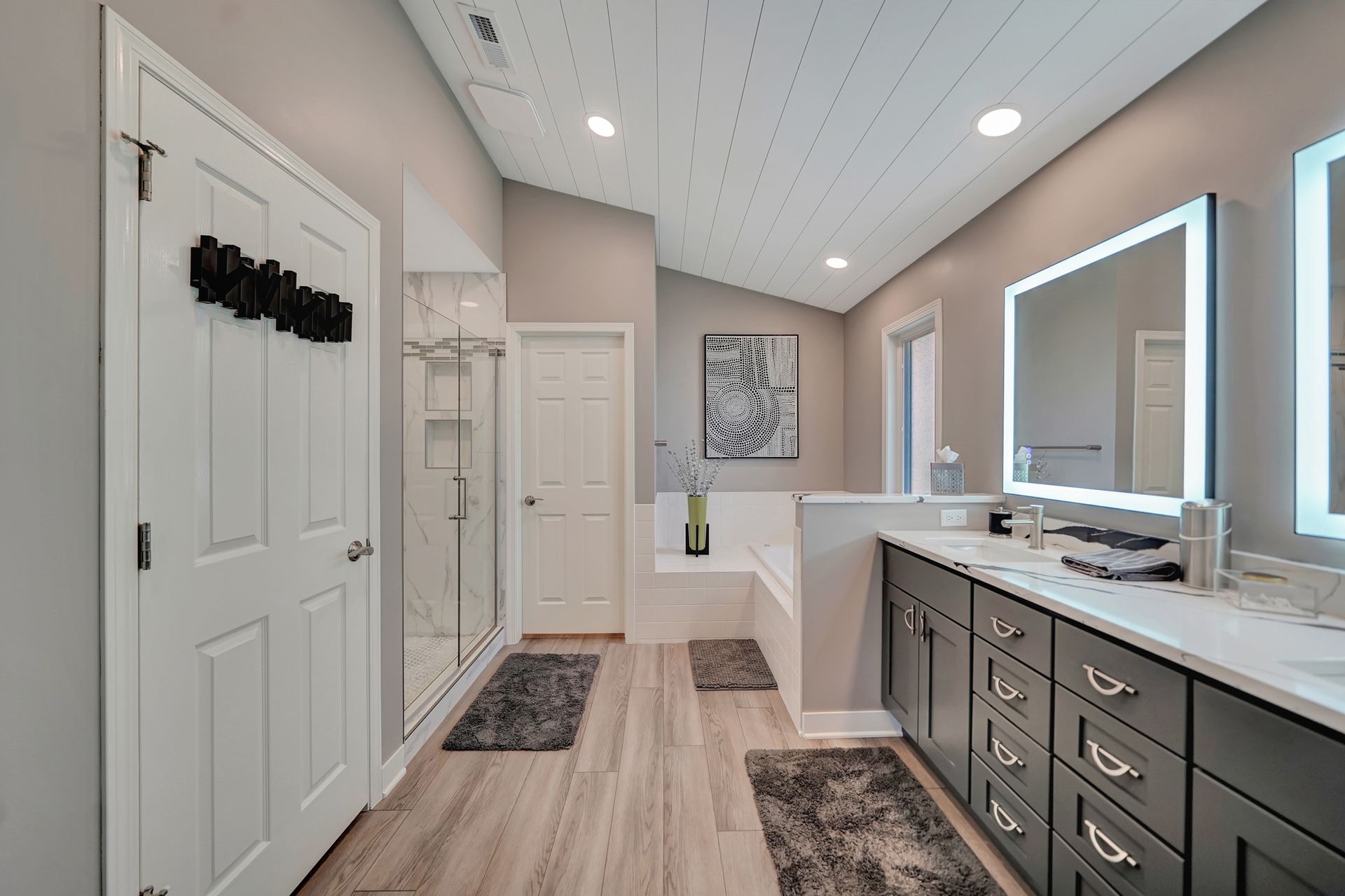 Modern bathroom with gray cabinets, white countertops, and wood-look tile.
