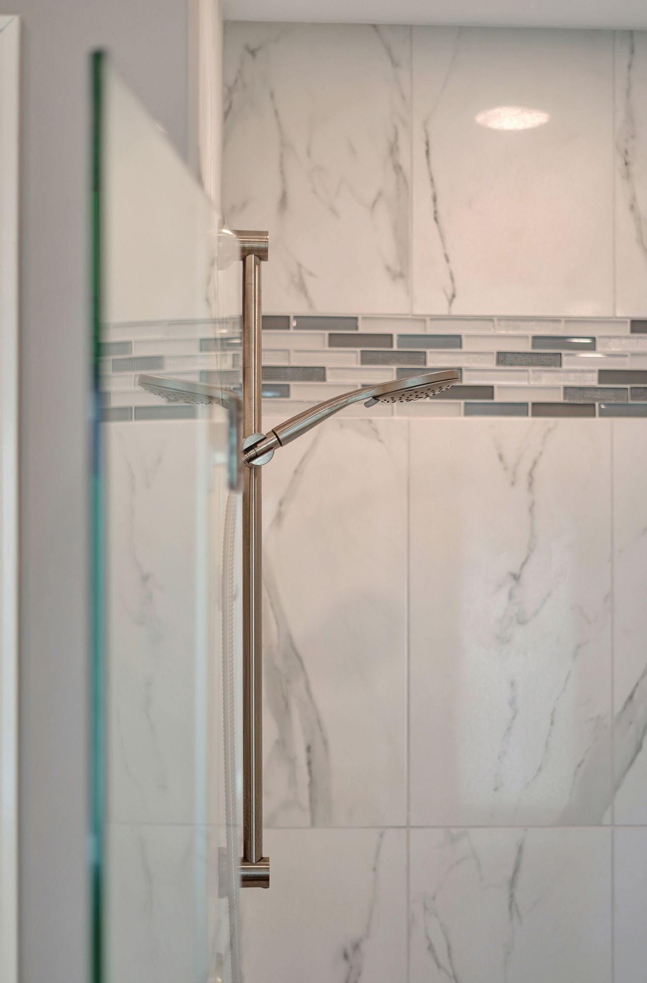 Shower with marble-look tile, glass door, and a silver shower head.