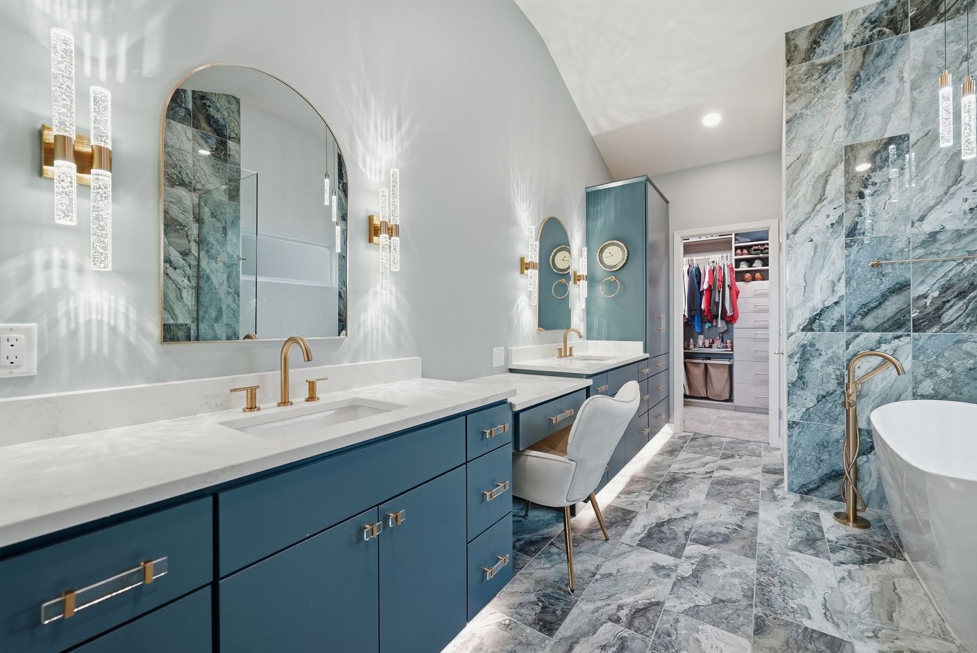 Bright blue-and-white bathroom with marble floors, dual sinks, and a walk-in shower with gold fixtures.
