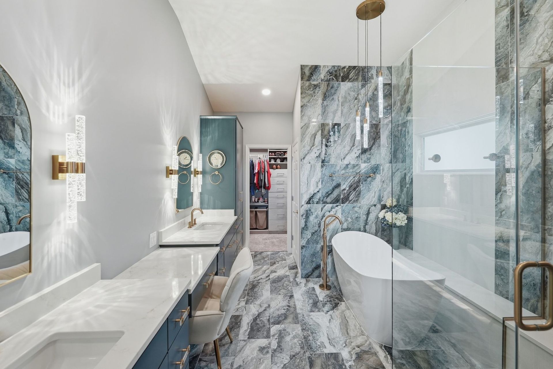 Modern bathroom with marble shower, double vanity, and glass enclosure in white and gold tones