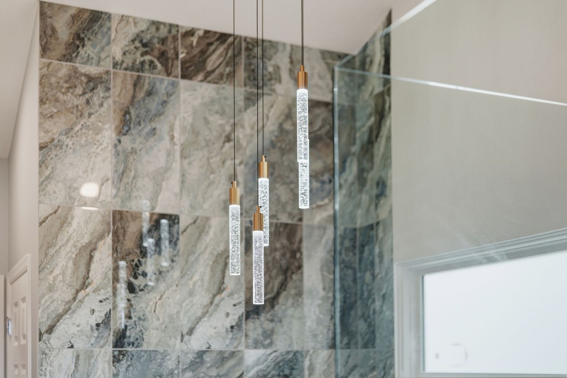 Modern shower with gray marble-look tile, glass doors, and hanging shower labels