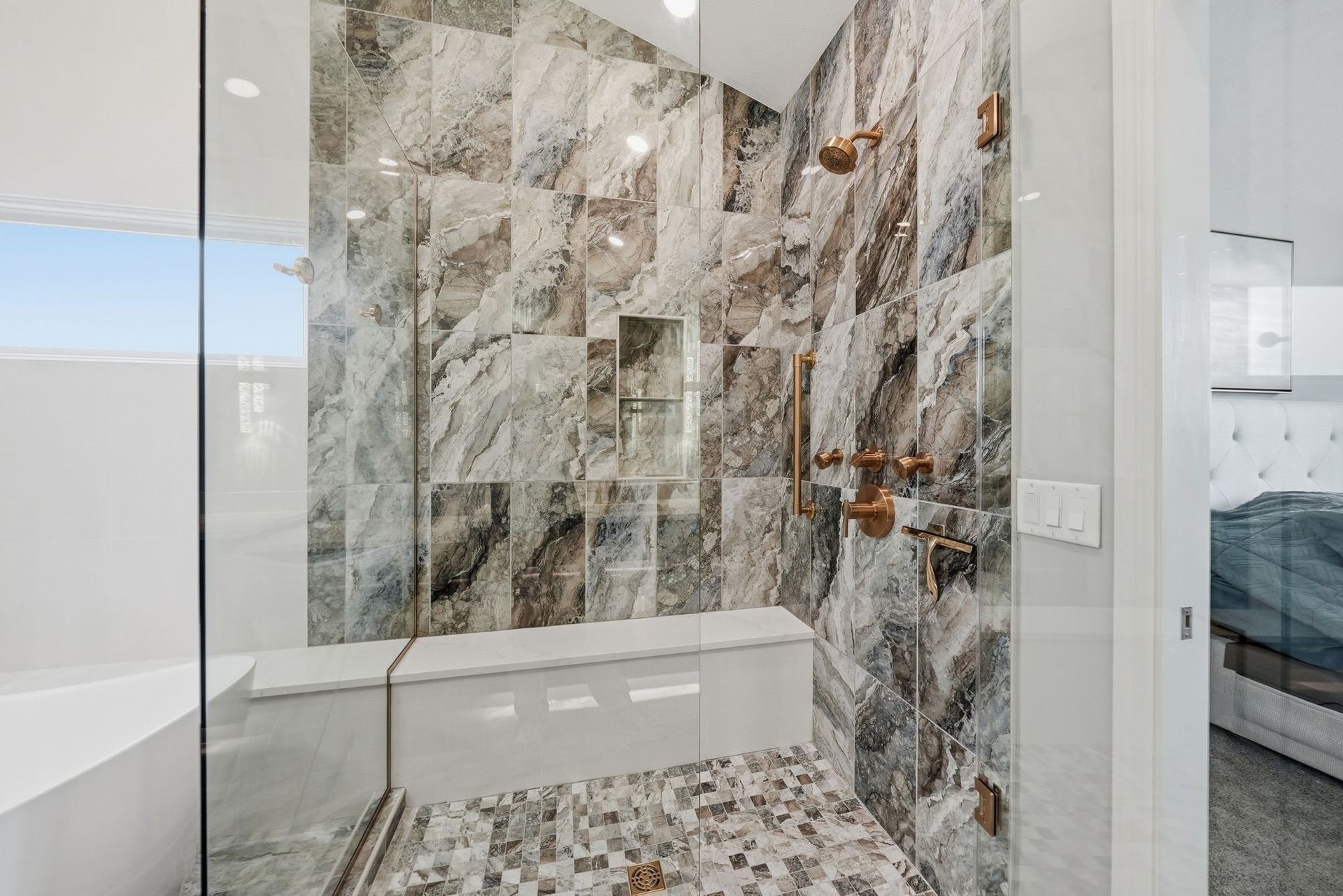 Modern bathroom with glass shower, marble tile, and a freestanding tub