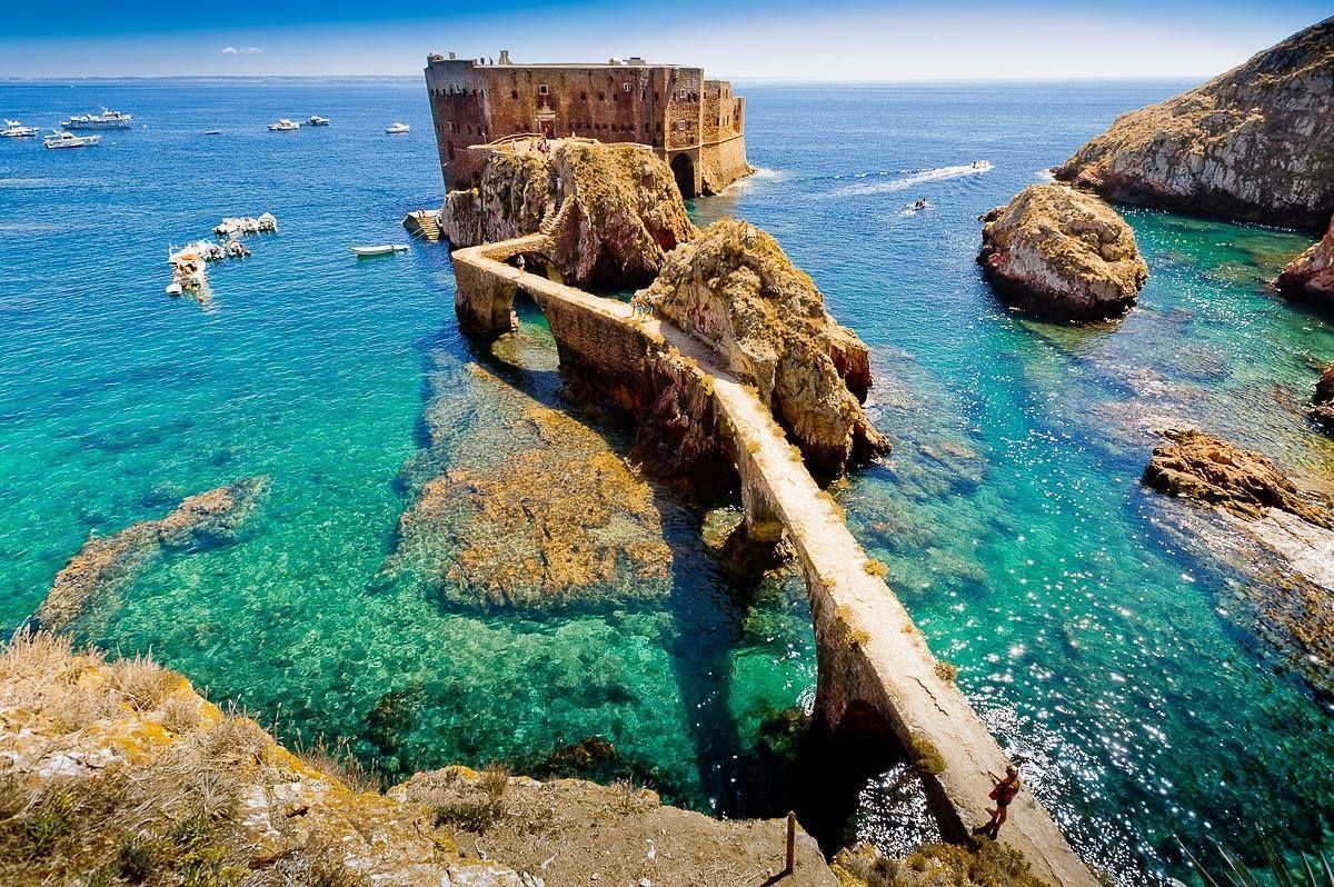 A bridge leading to a small island in the middle of the ocean.
