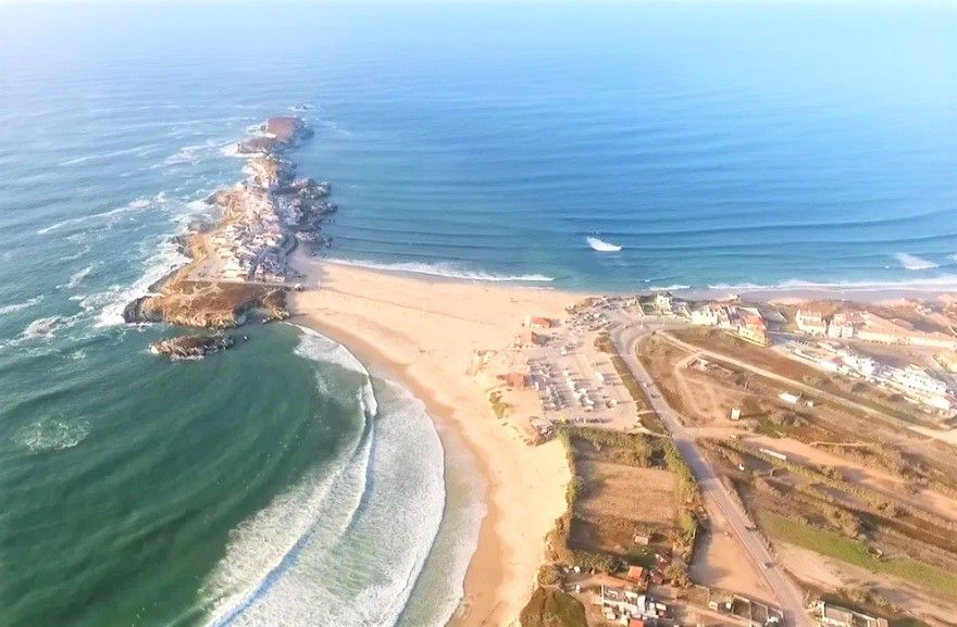 An aerial view of a beach with waves crashing on the shore.