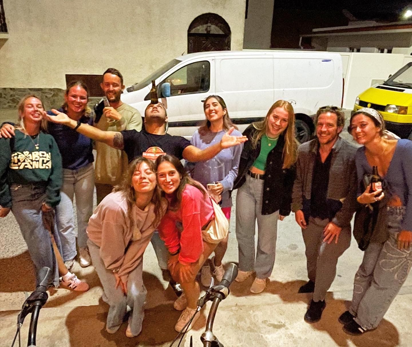 A group of people are posing for a picture in front of a van.
