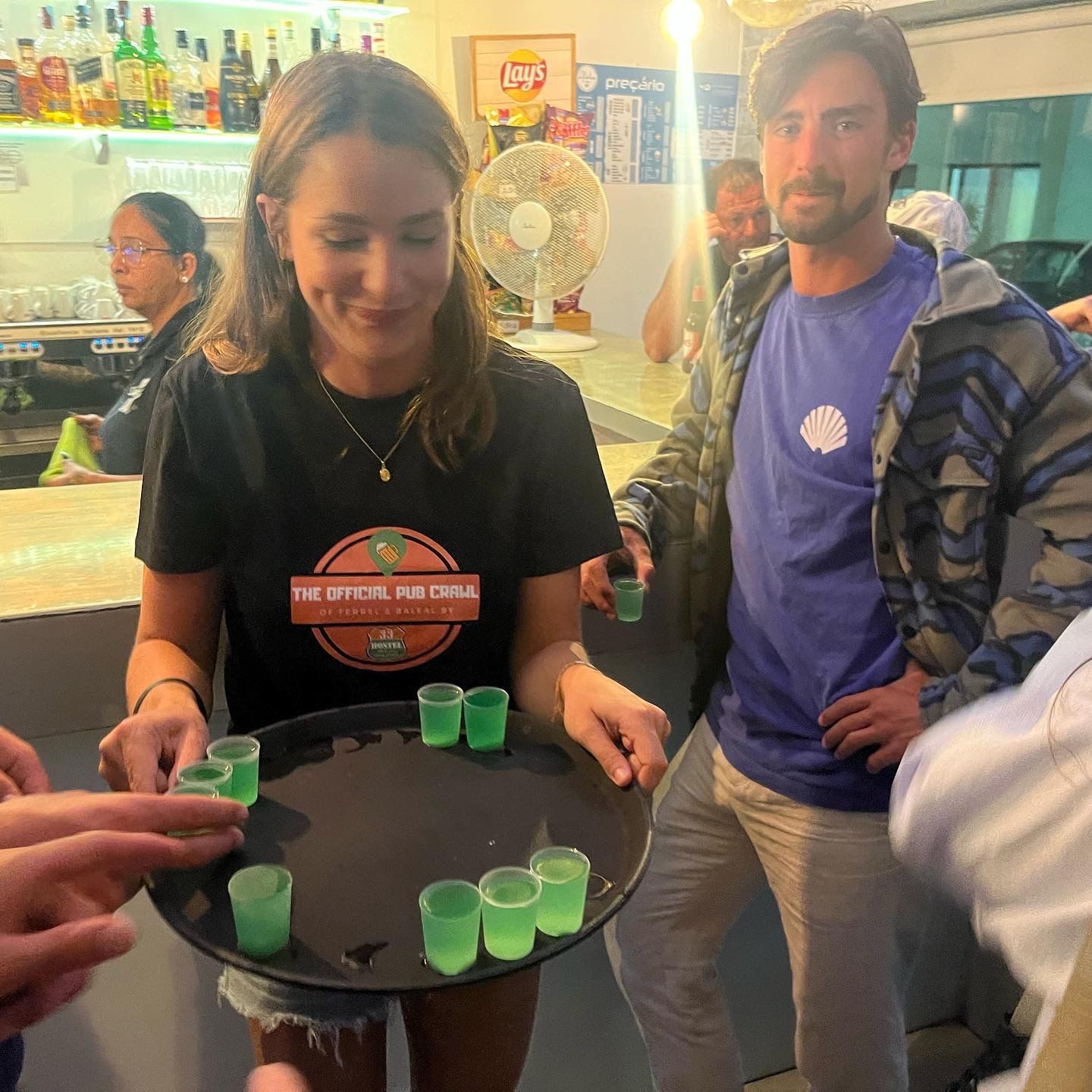 A man and a woman holding a tray of shot glasses