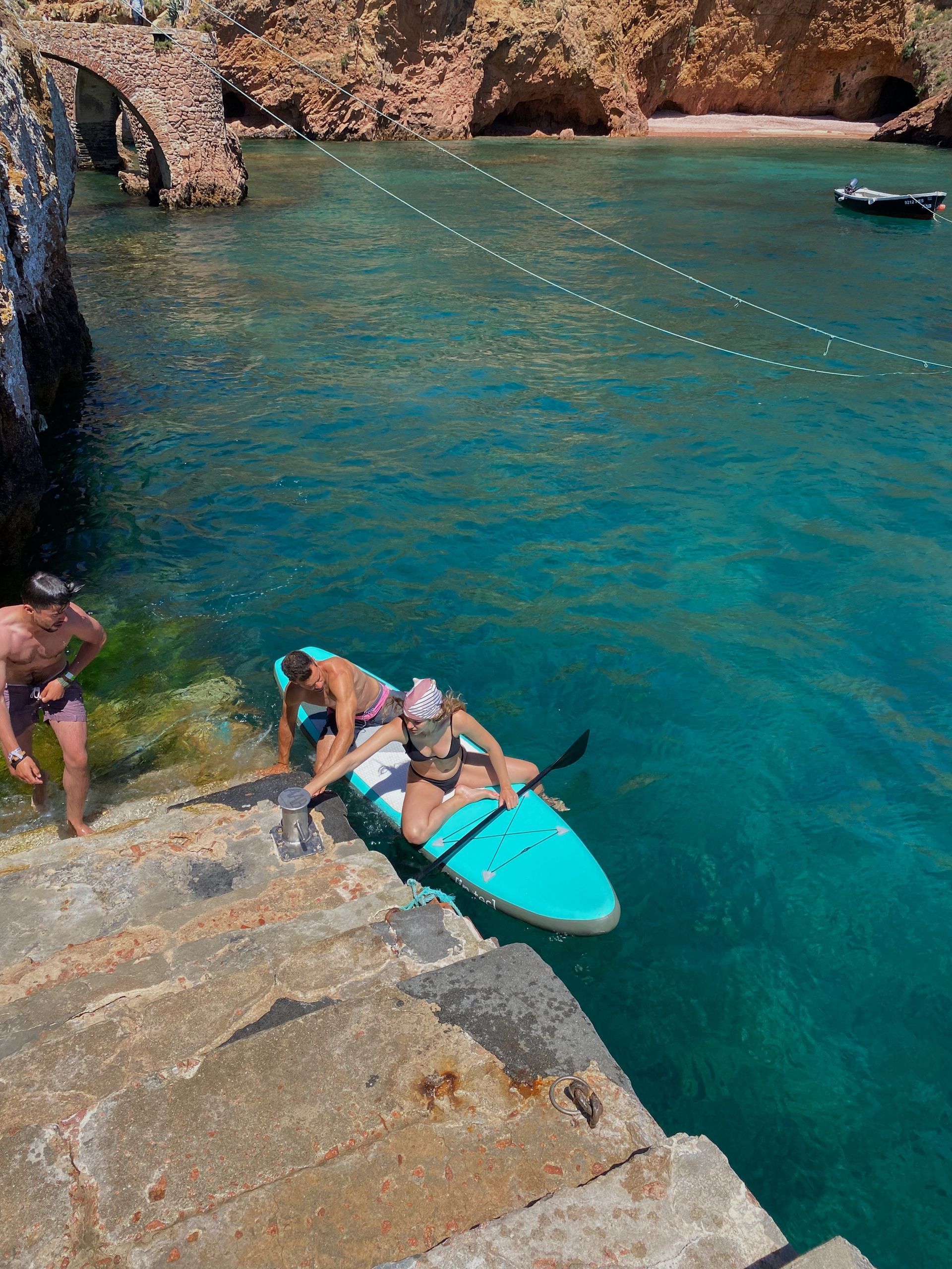 A man and a woman are standing next to a kayak in the water.
