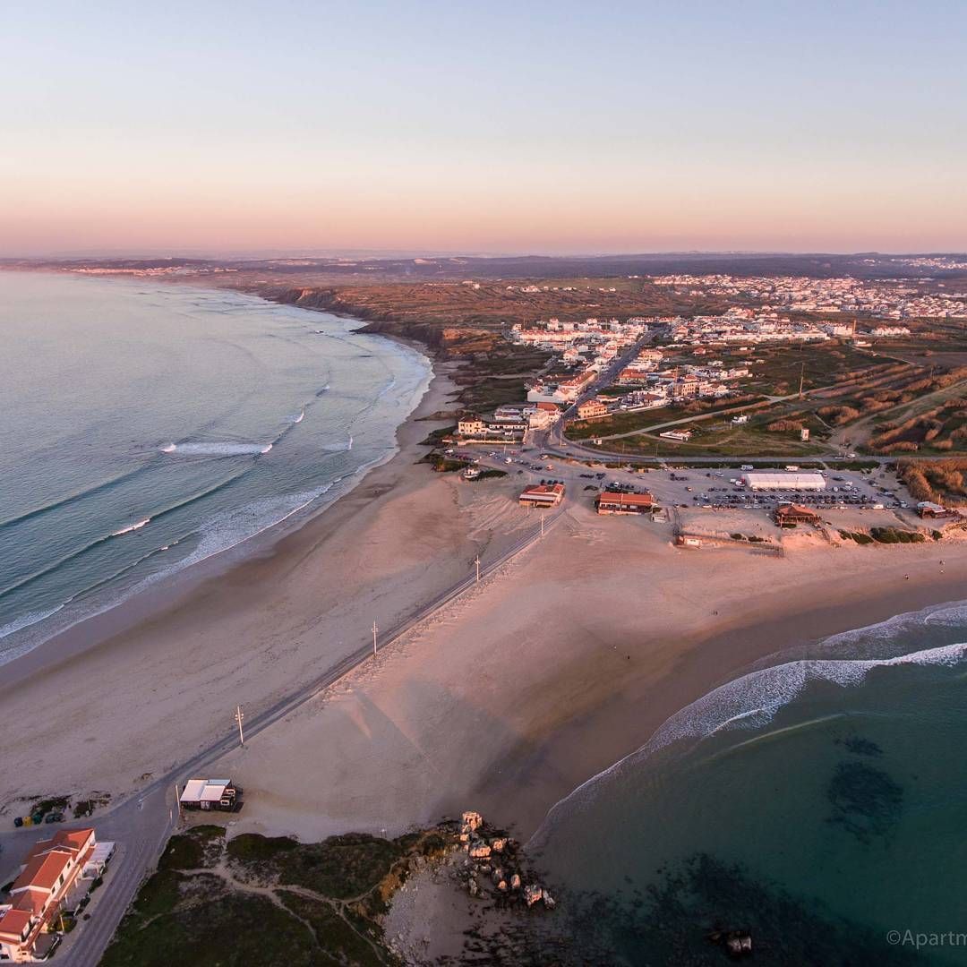 An aerial view of a beach and ocean at sunset.