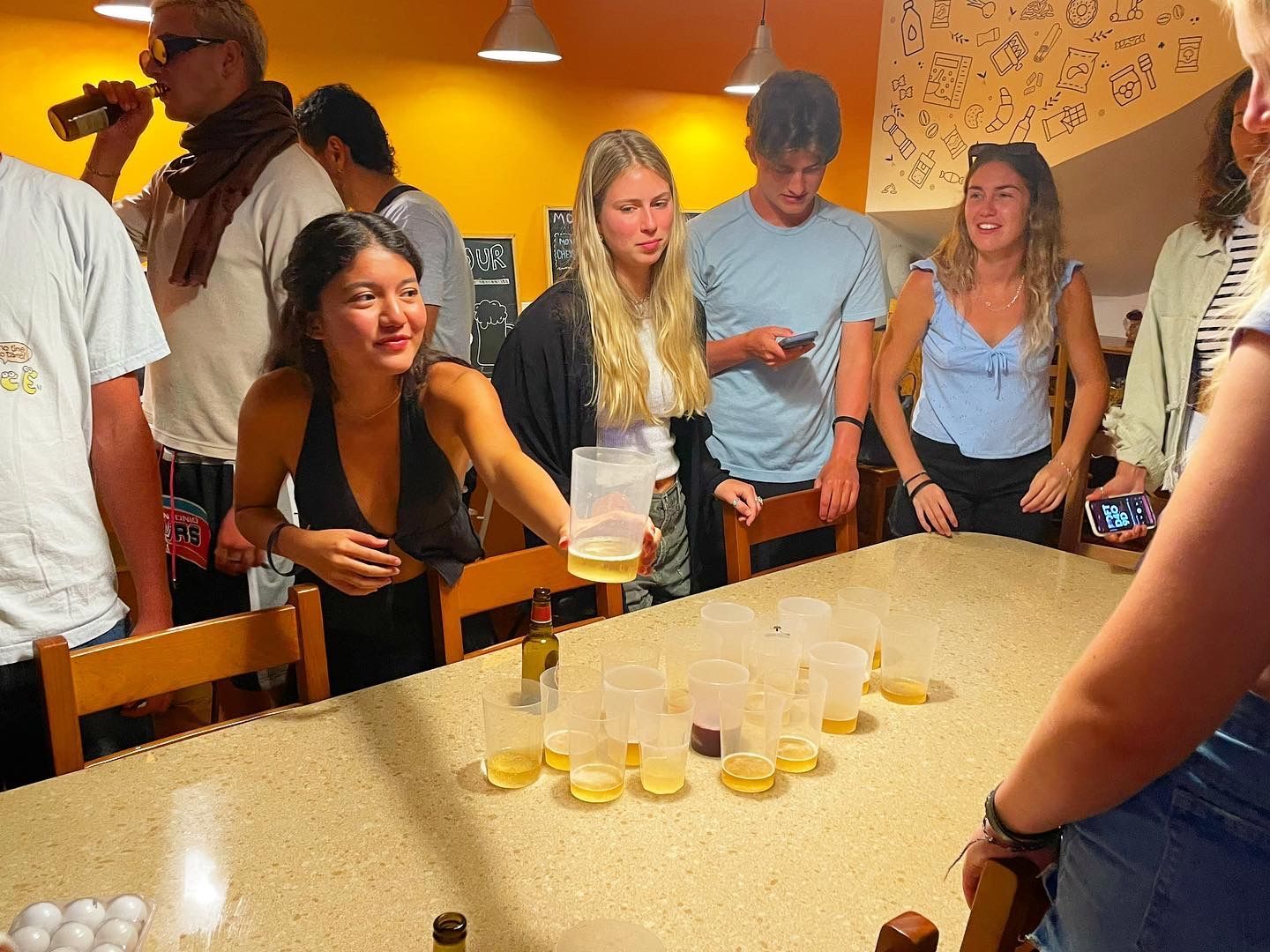 A group of people are sitting around a table playing beer pong.