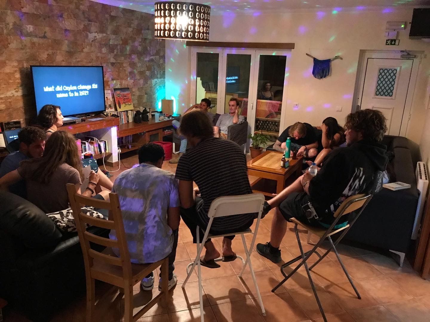A group of people are sitting around a table in a living room.