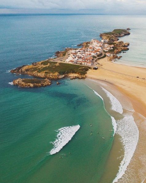 An aerial view of a beach with waves crashing on the shore.