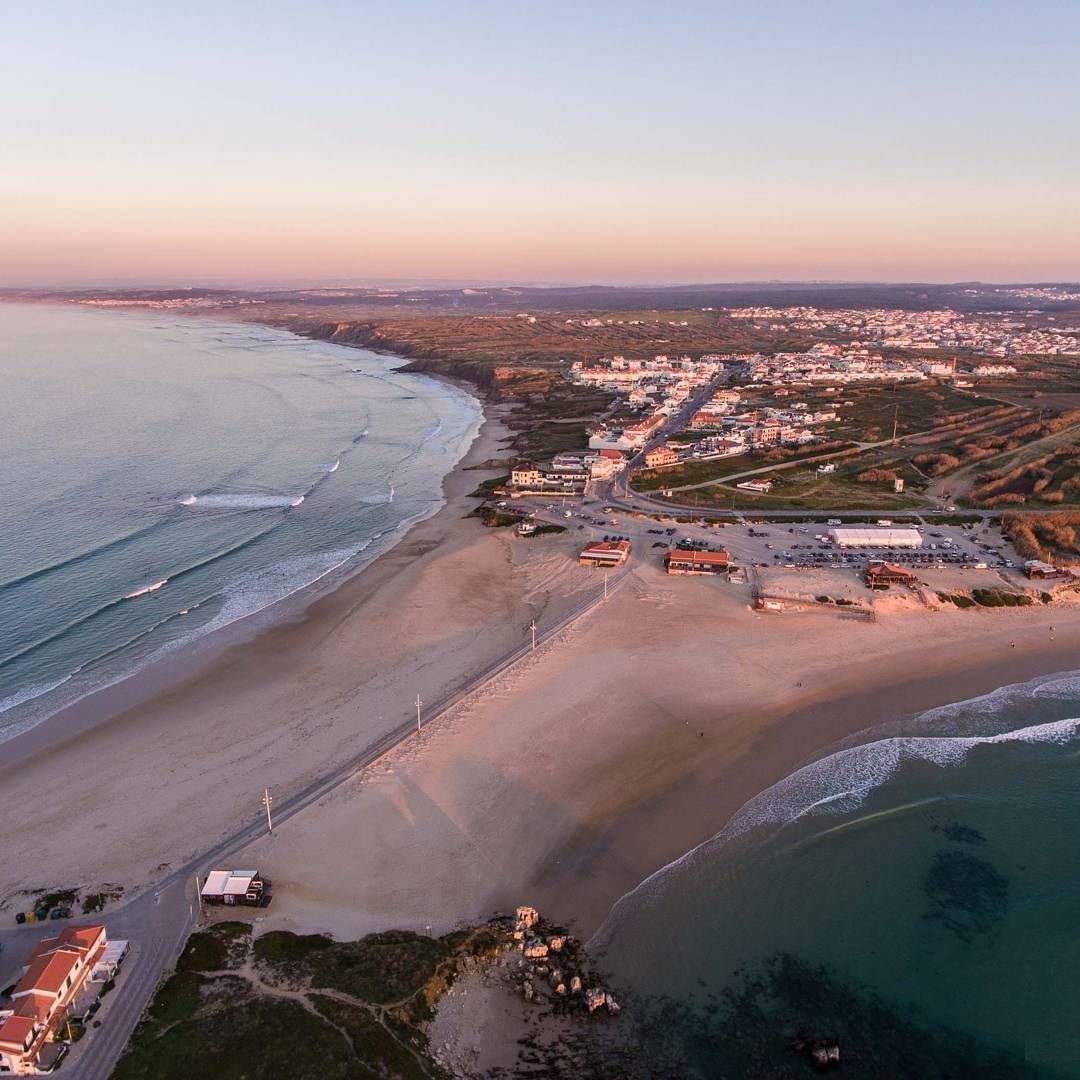 An aerial view of a beach and ocean at sunset.