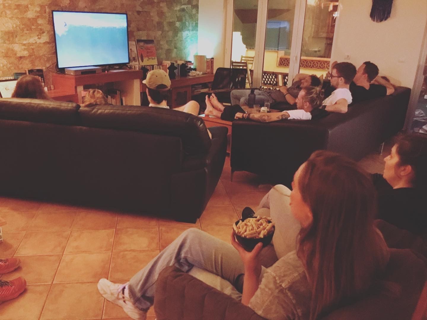 A group of people are sitting in a living room watching tv
