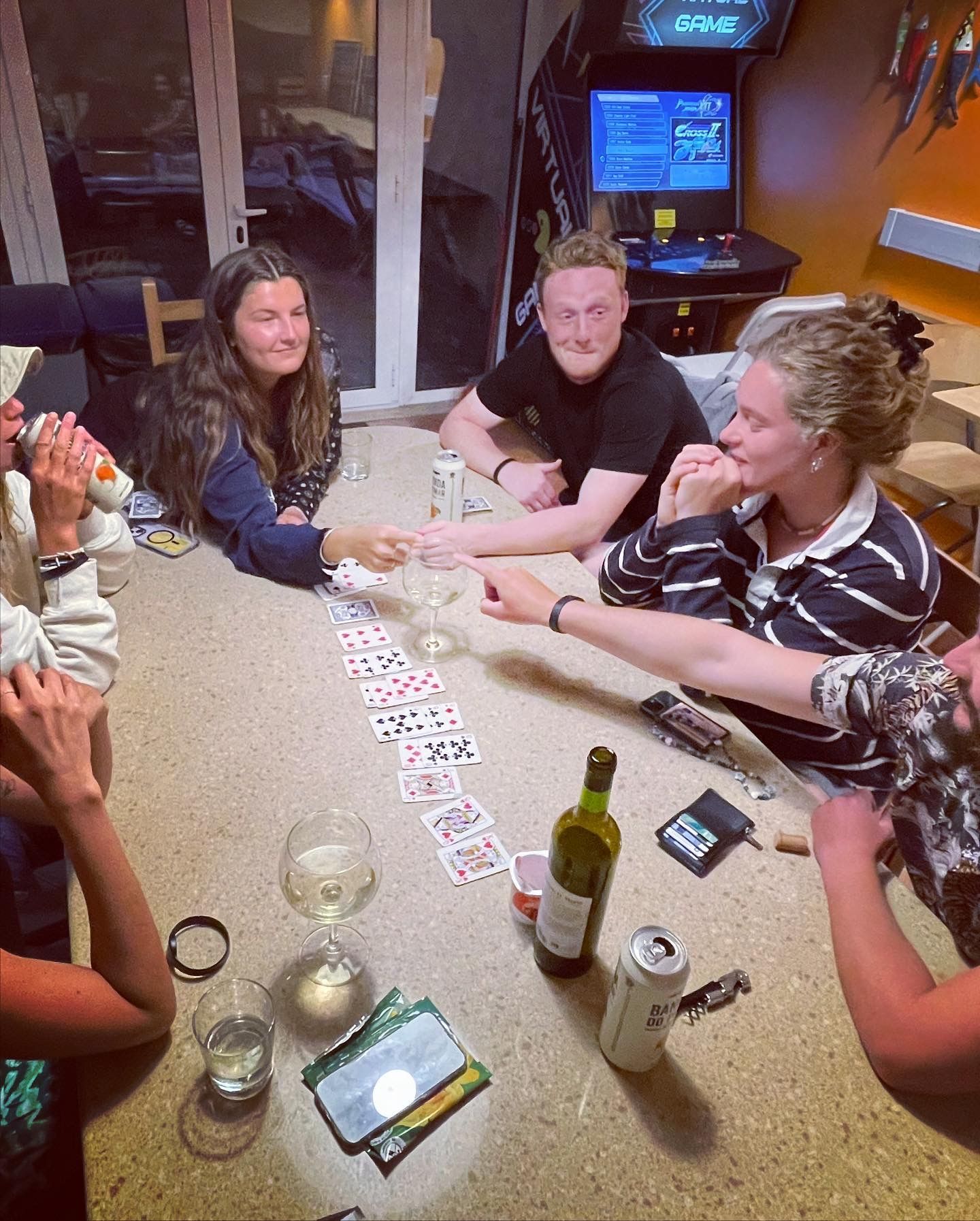 A group of people are sitting around a table playing cards.