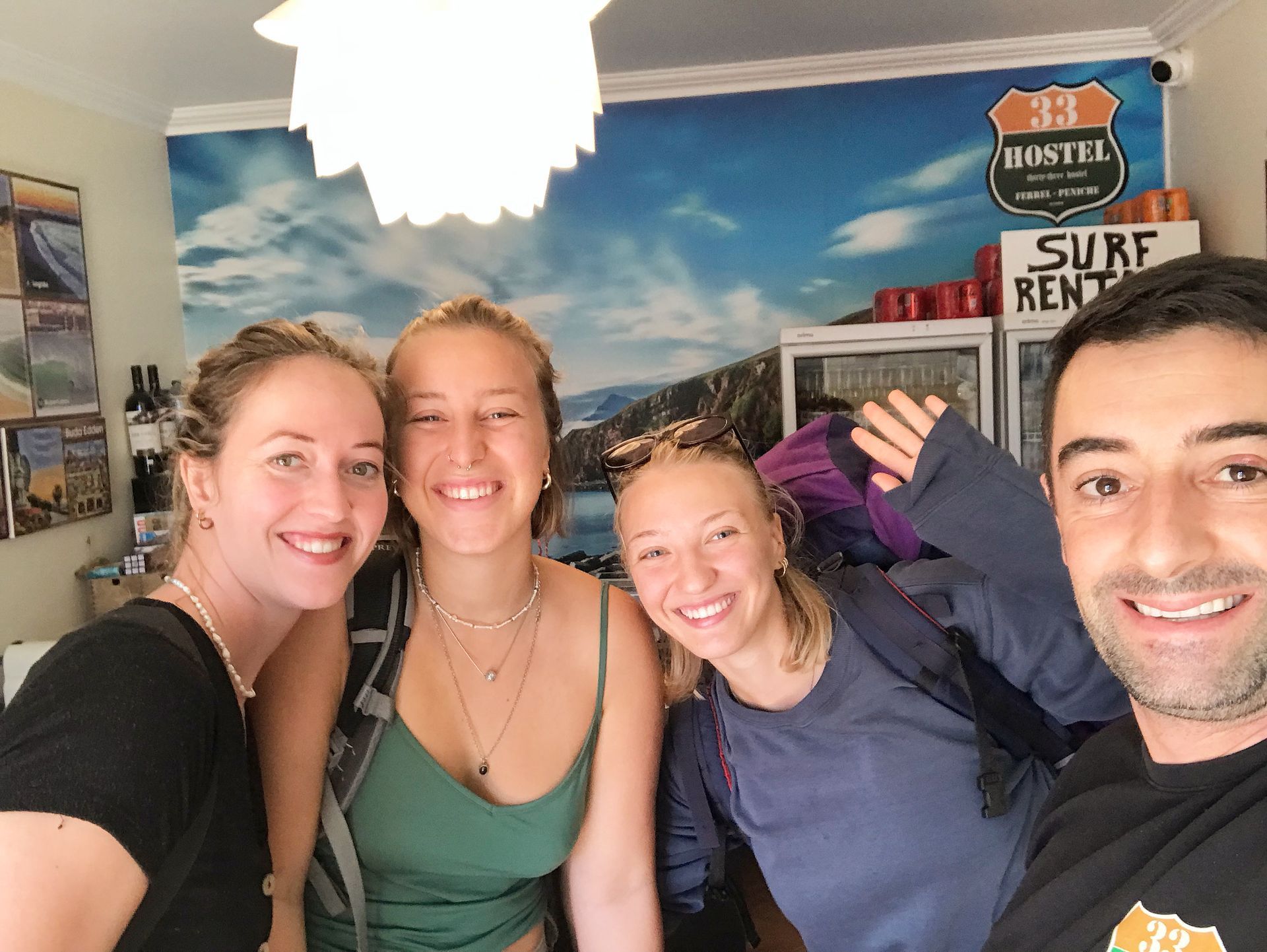 A group of people are posing for a picture in front of a surf rental sign.