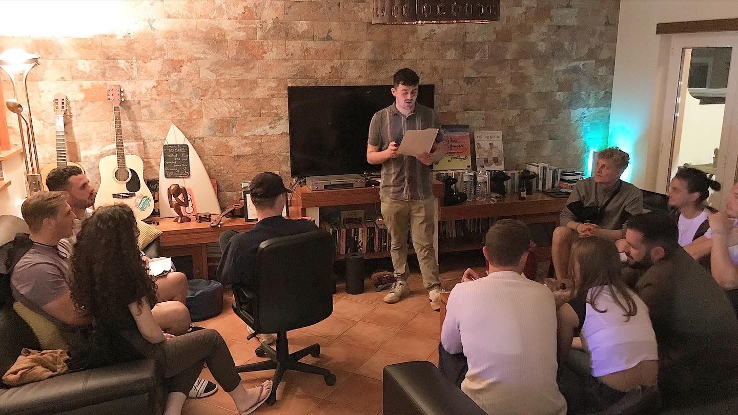 A man is giving a presentation to a group of people in a living room.