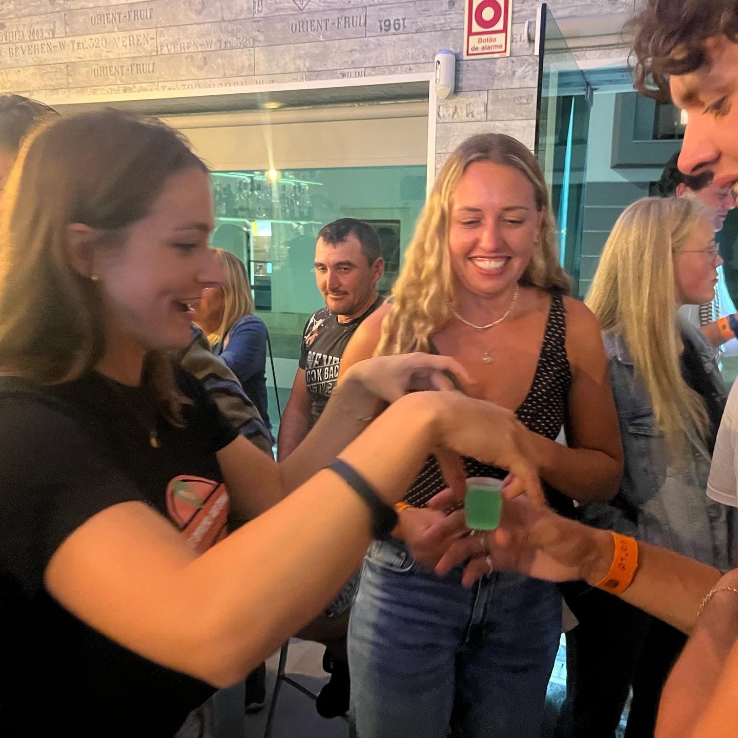 A group of people are standing around a woman holding a shot glass