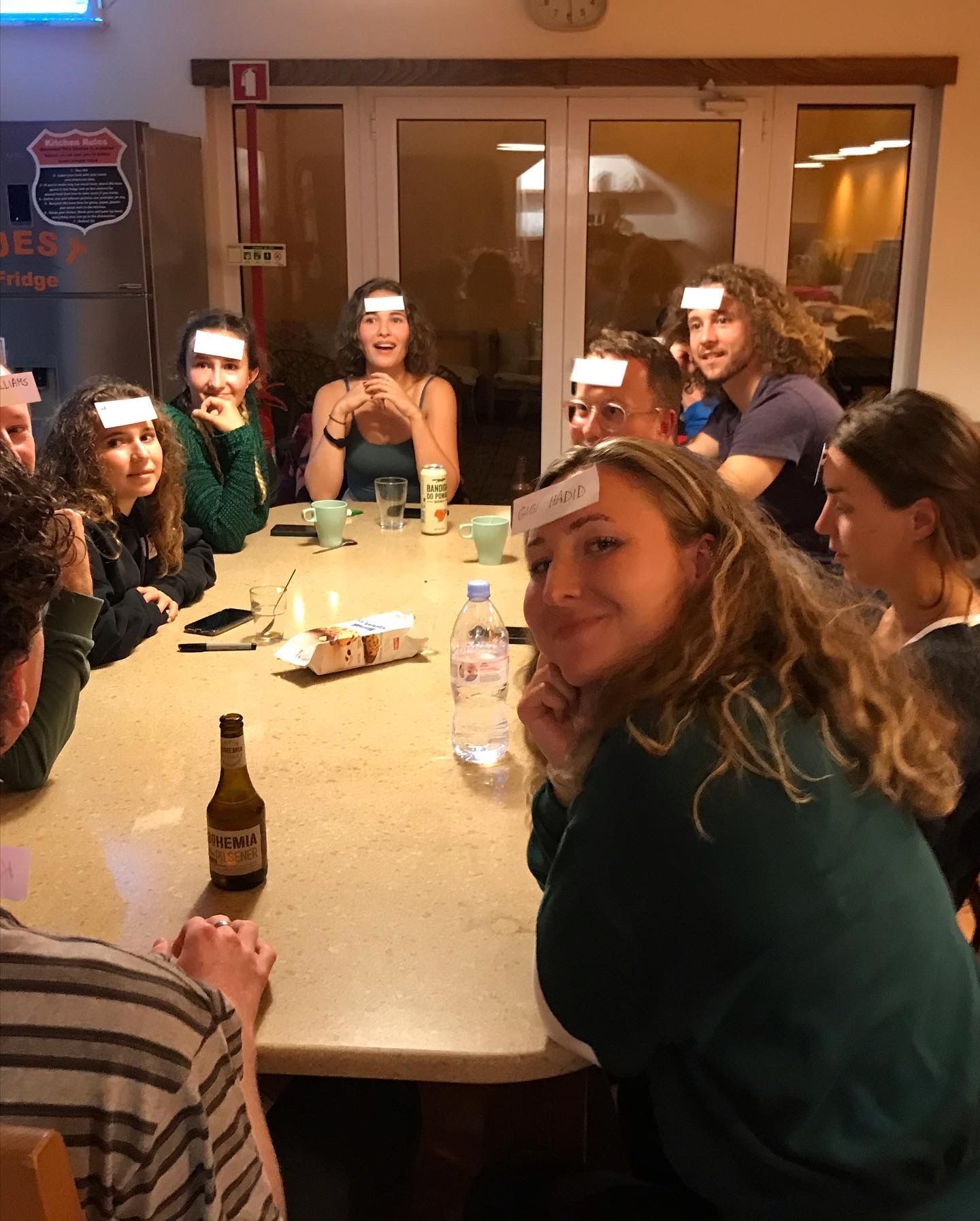 A group of people are sitting around a table with cards on their faces.