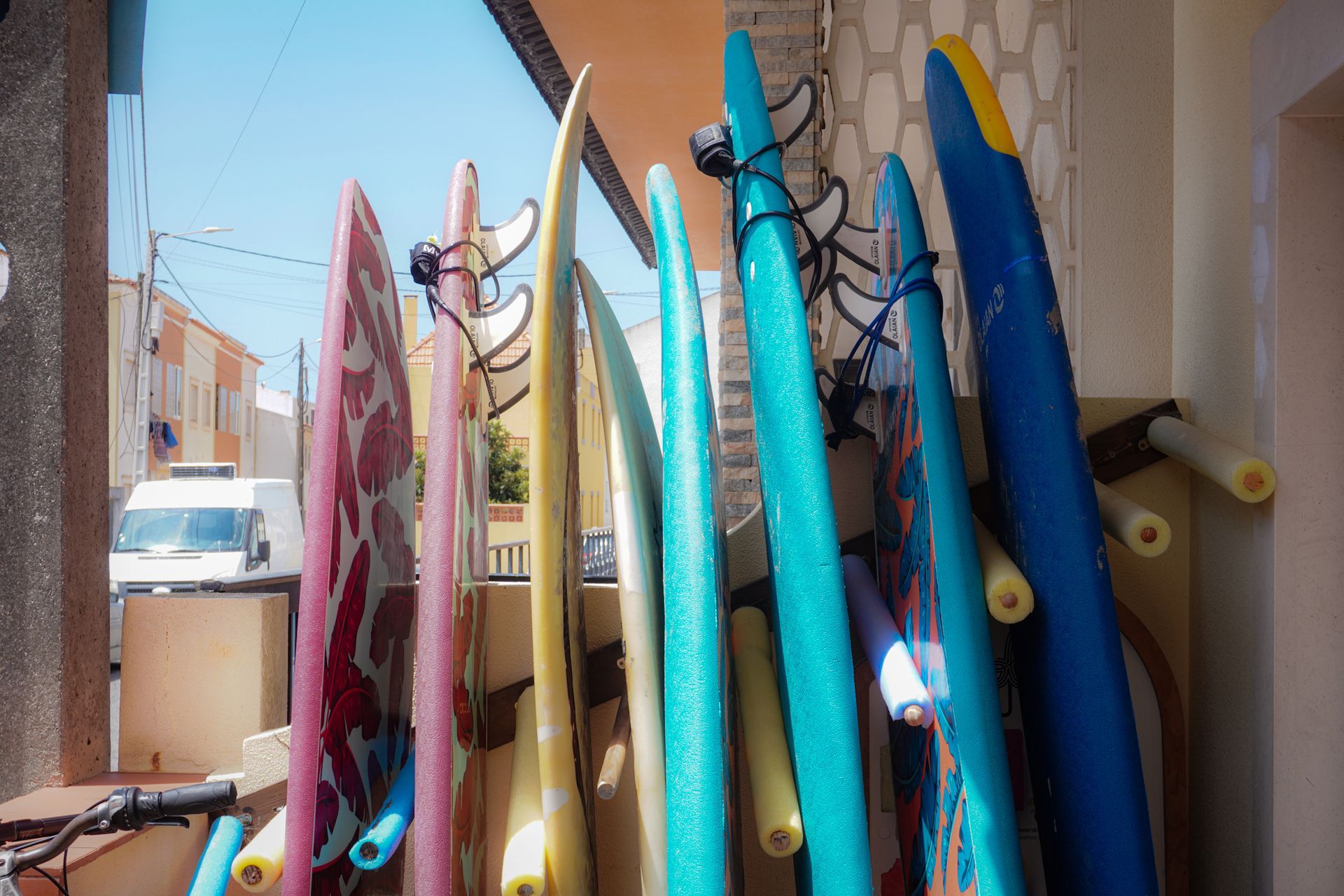 A bunch of surfboards are hanging on a rack outside