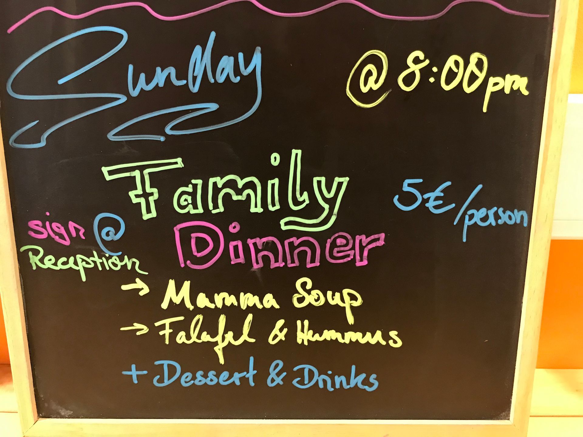 A chalkboard advertising a family dinner at 8:00 pm