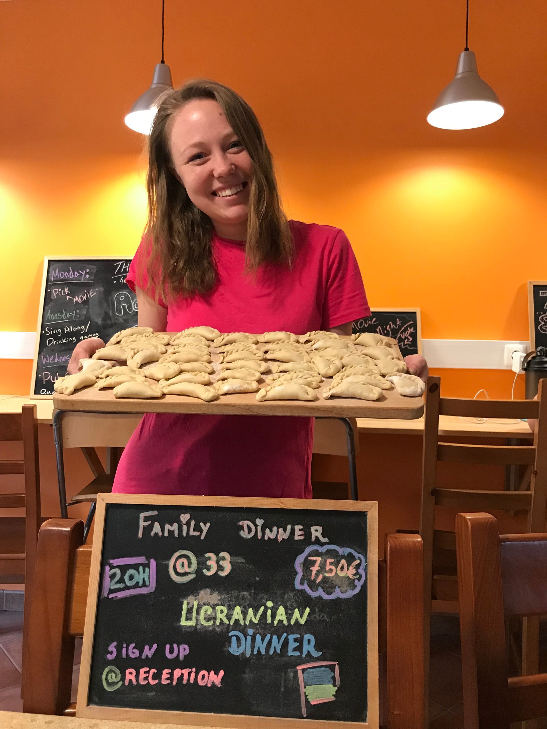 A woman holding a tray of food next to a sign that says family dinner