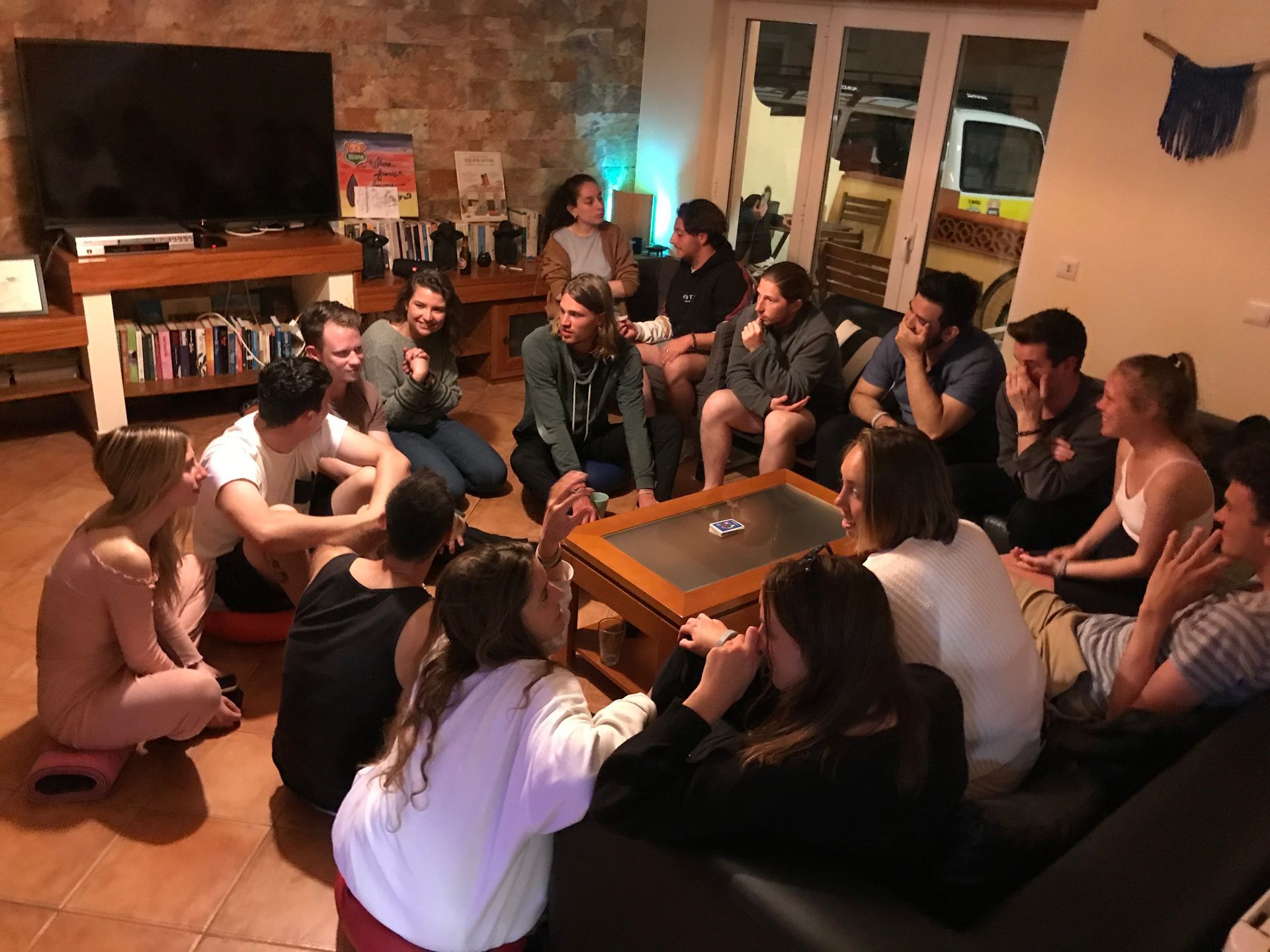 A group of people are sitting around a table in a living room.