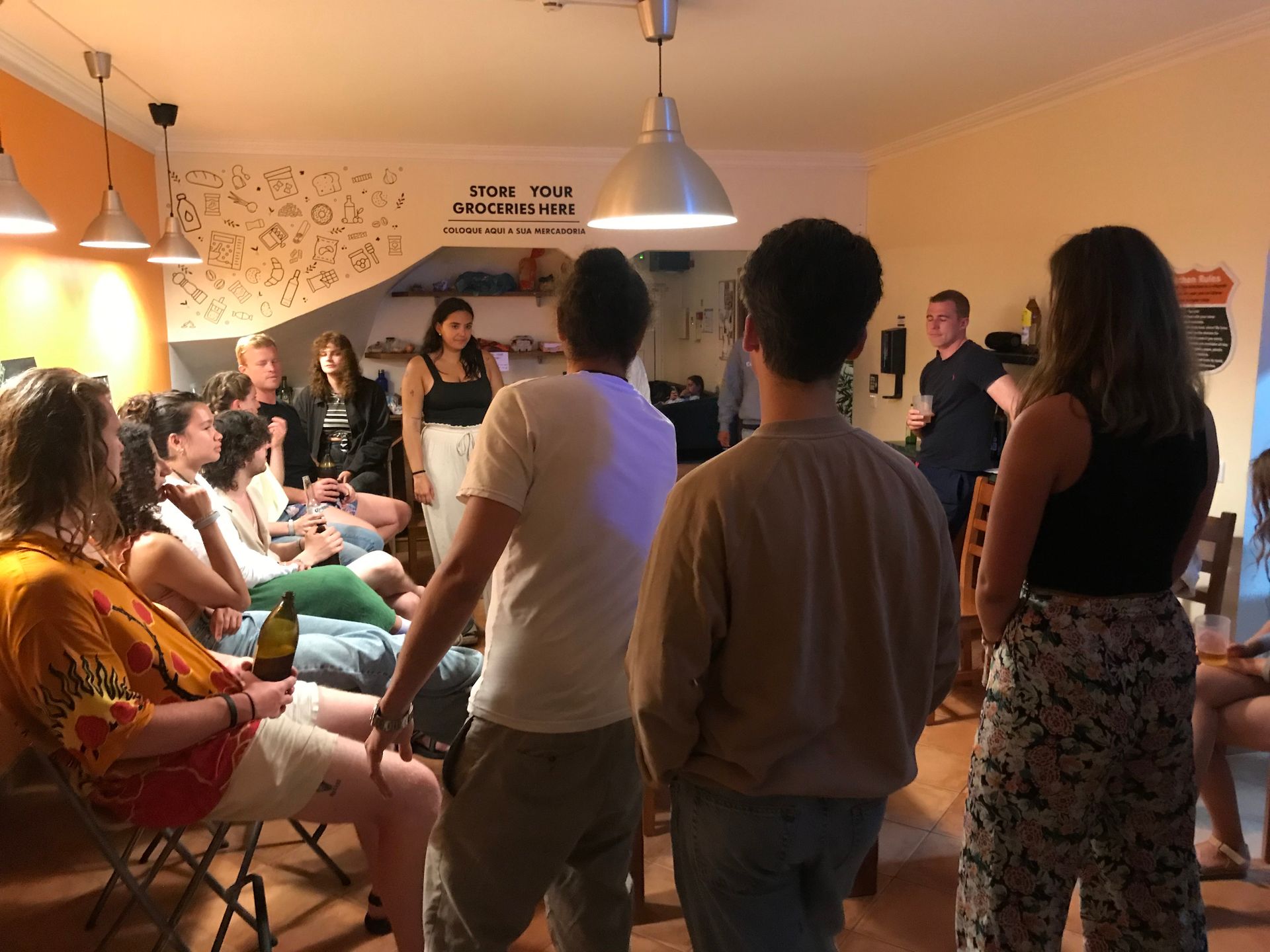 A group of people are gathered in a room with a sign on the wall that says 