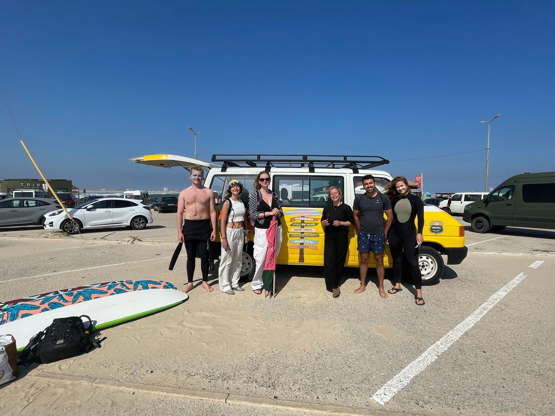 A group of people are standing in front of a yellow van in a parking lot.
