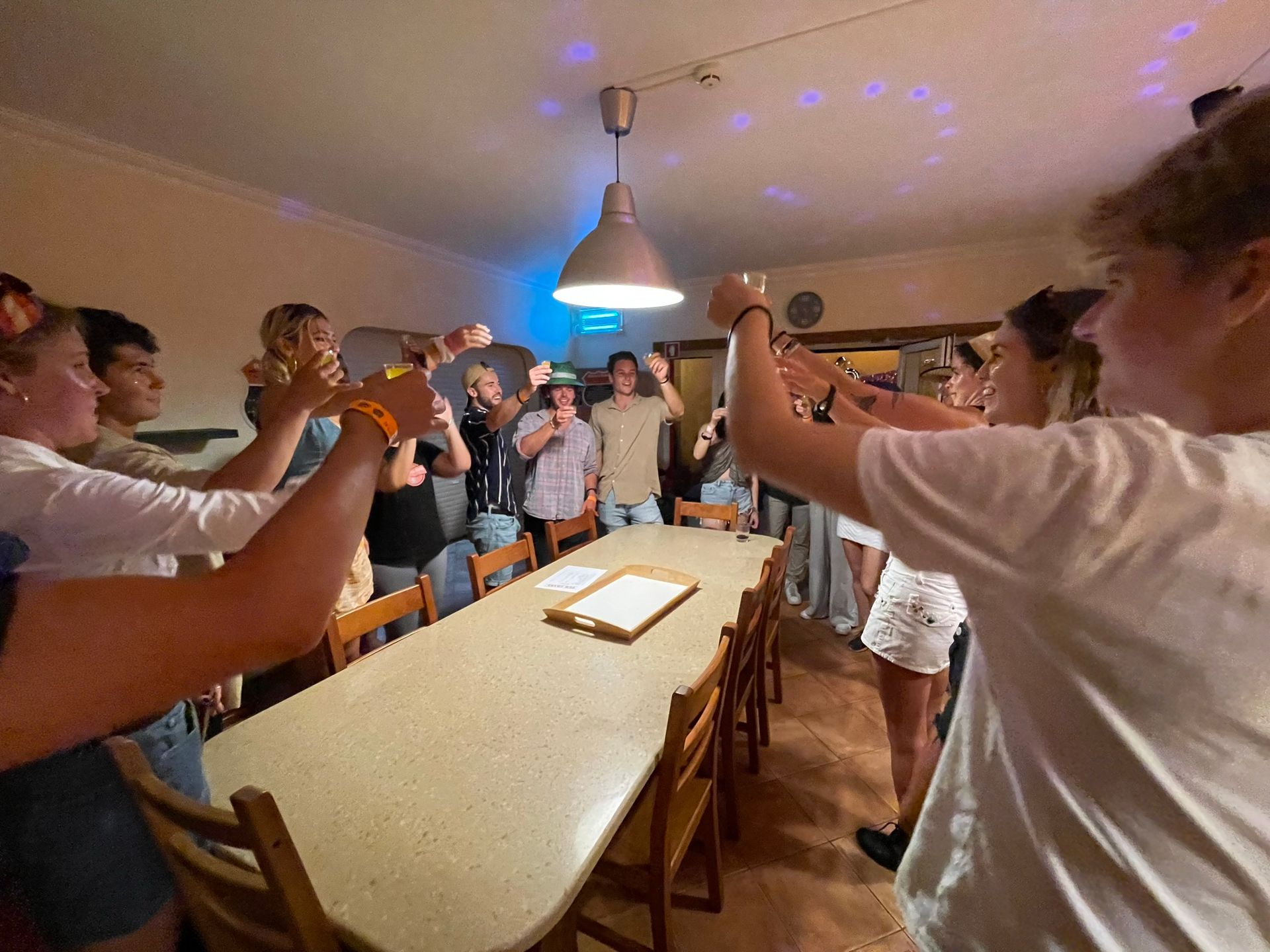 A group of people are standing around a table with their hands in the air.