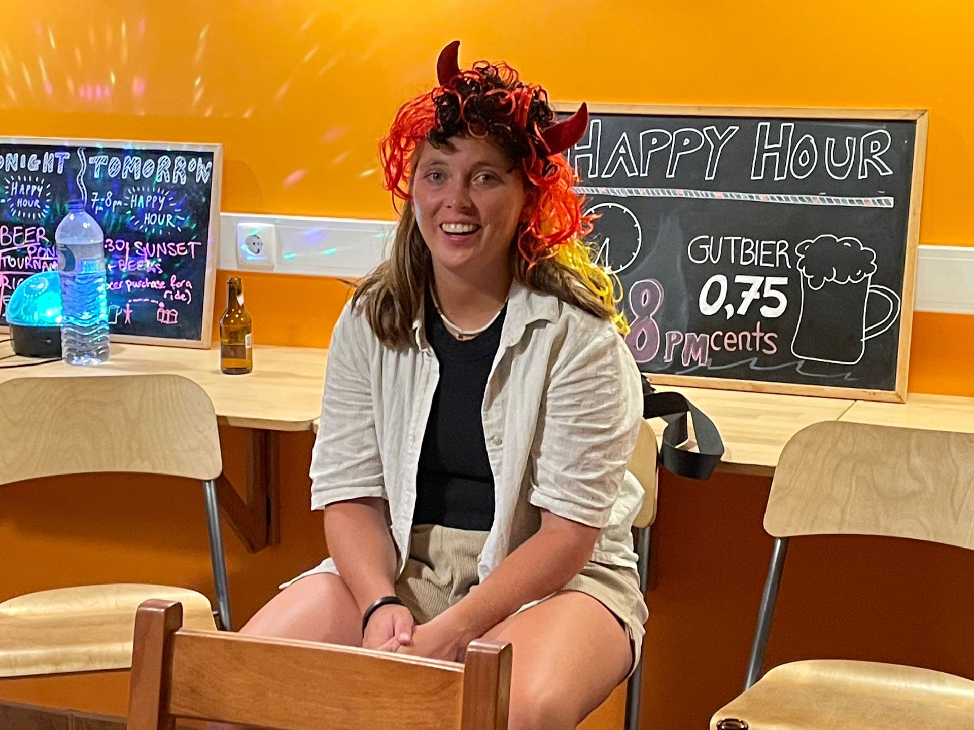 A woman is sitting in front of a sign that says happy hour