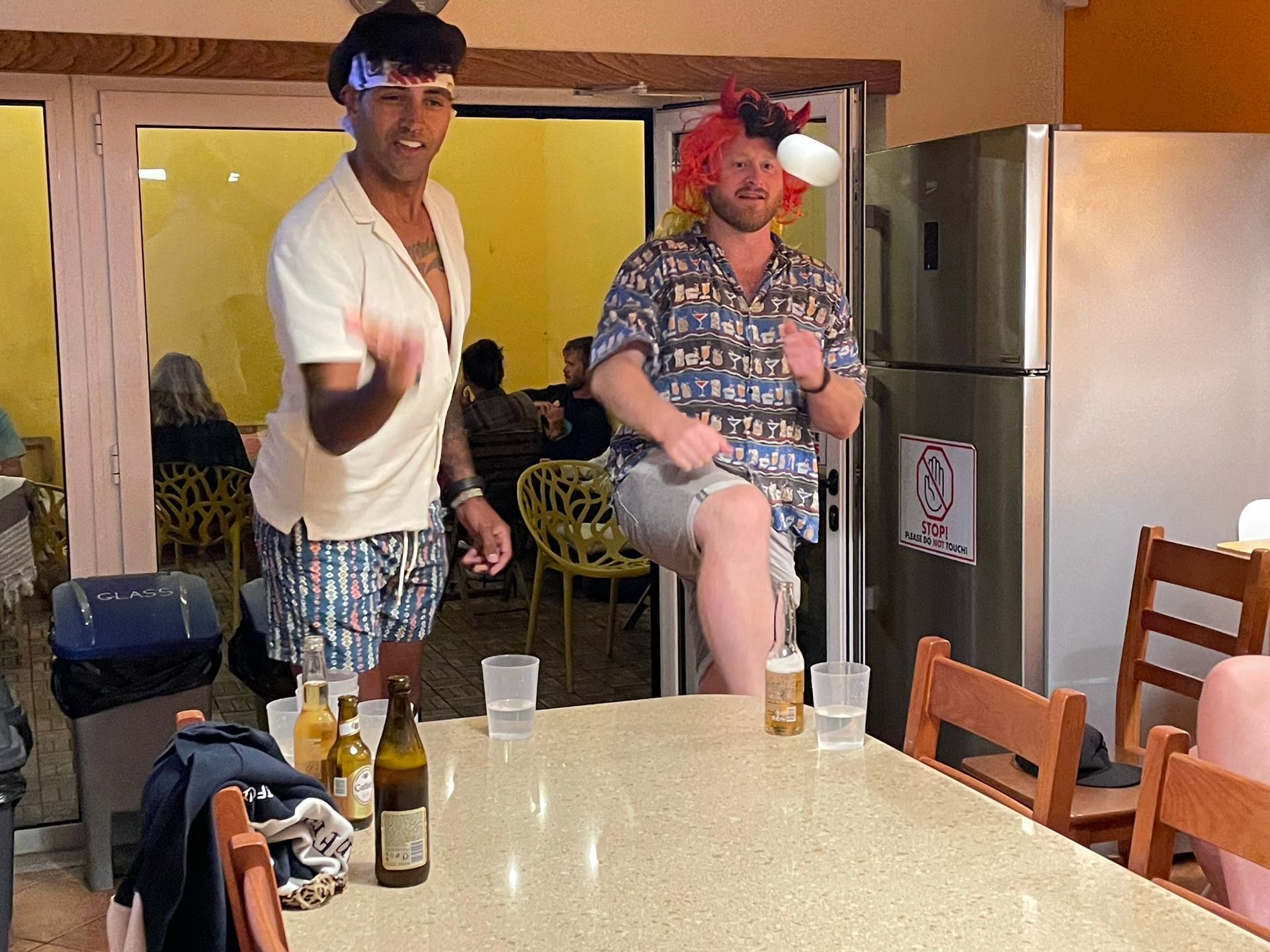 A man in a clown costume is standing next to a man in a white shirt