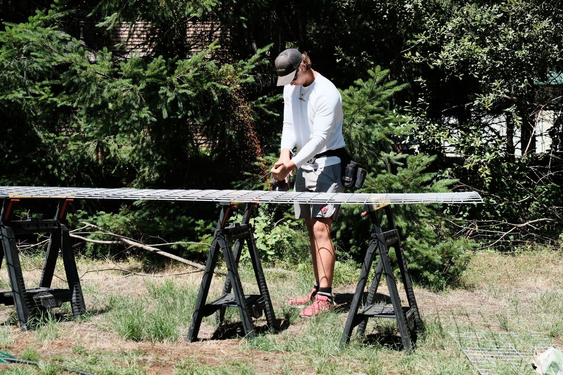 A man is cutting a piece of wood with a saw in a field. A man is cutting a piece of wood with a saw in a field.