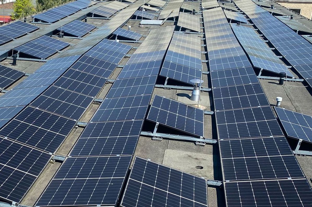 Rows of blue solar panels on a rooftop under bright daylight