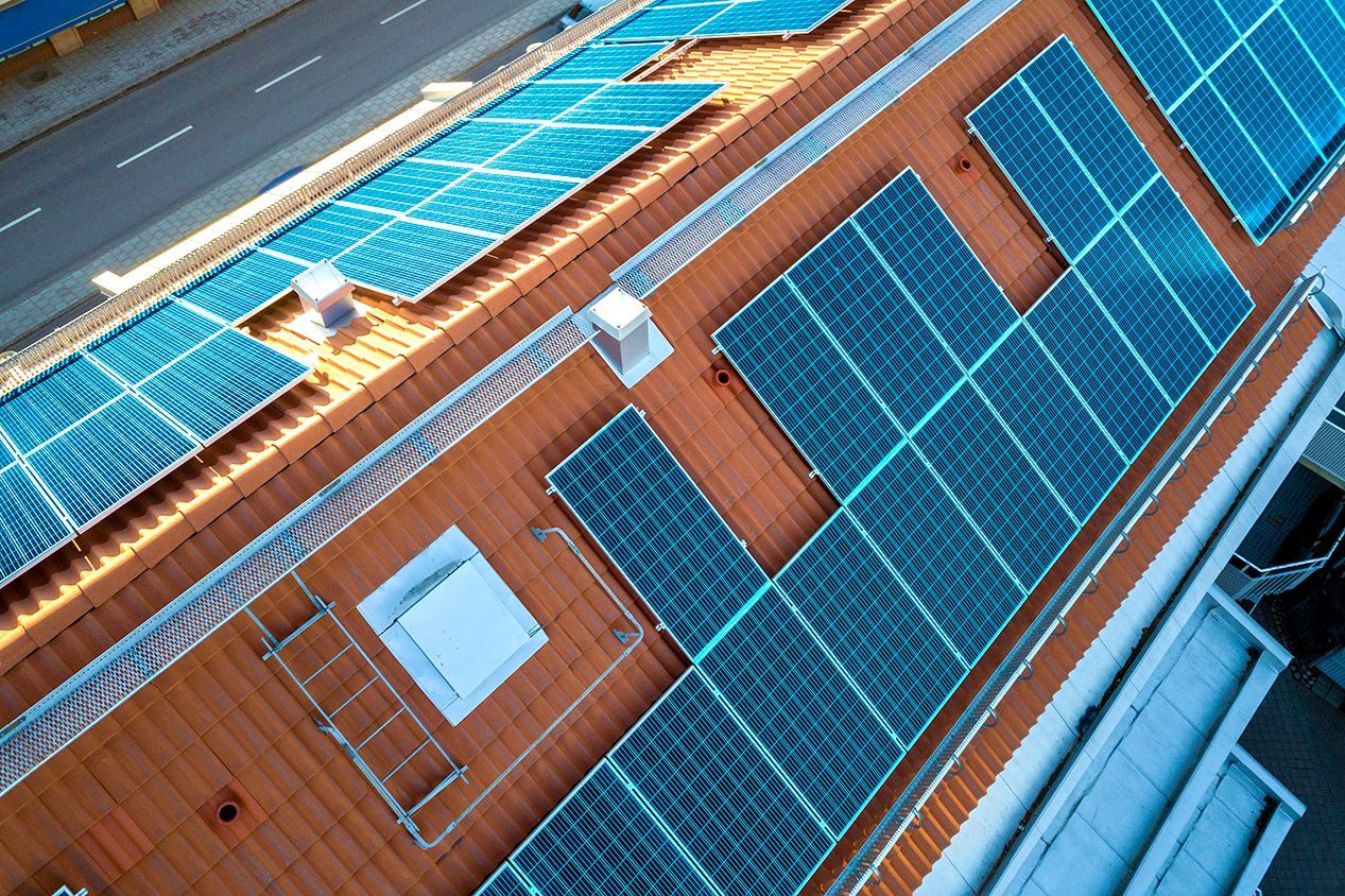 Aerial view of a building rooftop with blue solar panels and orange tiles