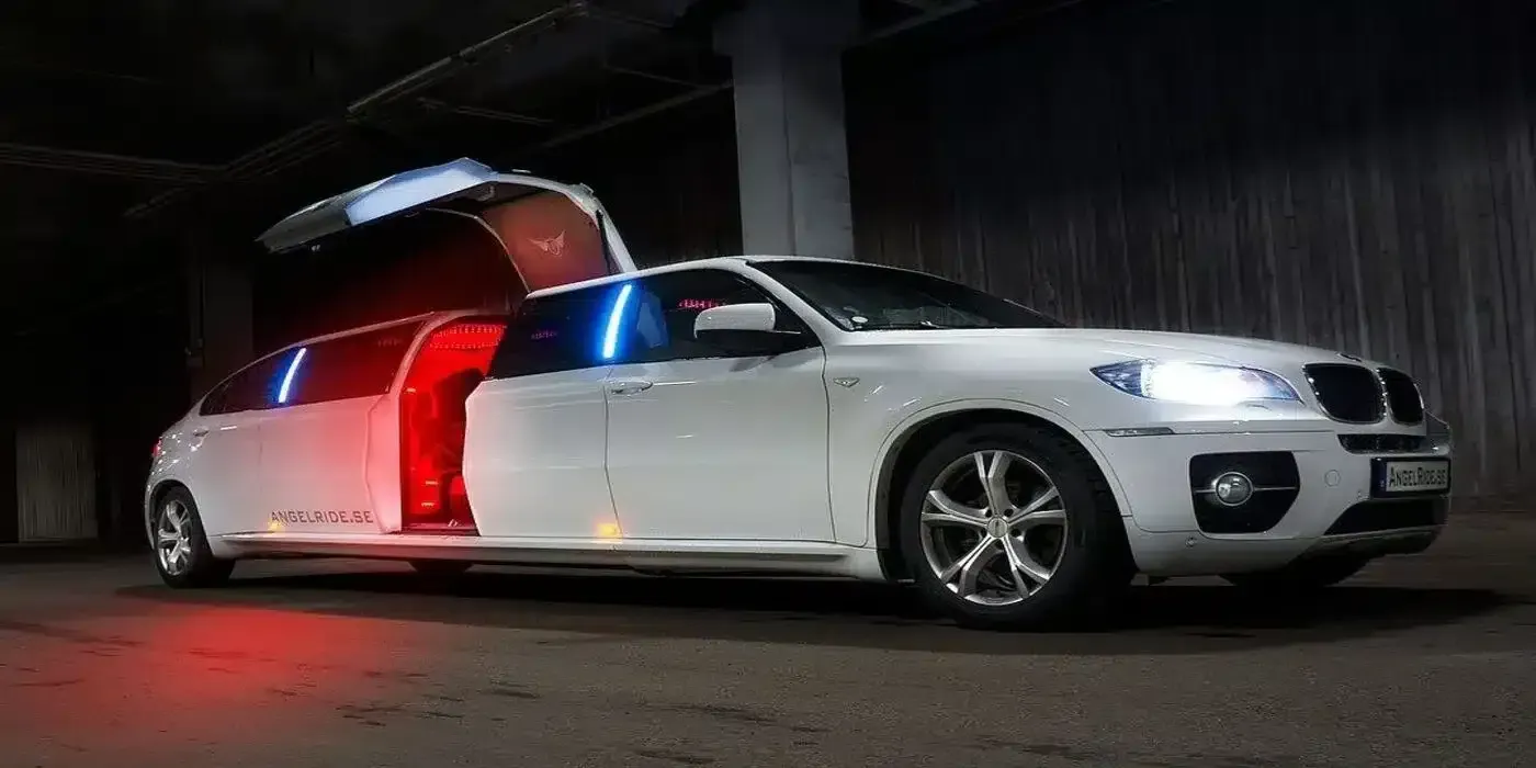 White limousine with gull-wing doors open, lit by red and blue lights.  Dark setting.