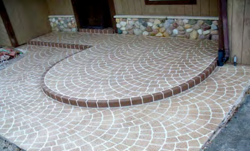 A concrete walkway with a curved staircase in front of a house.