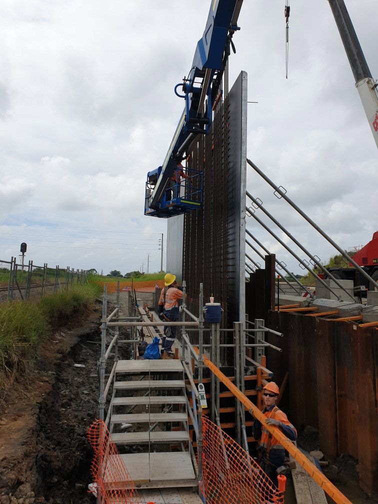 Construction workers building a steel retaining wall outdoors using cranes and scaffolding — Bampak In Gympie, QLD