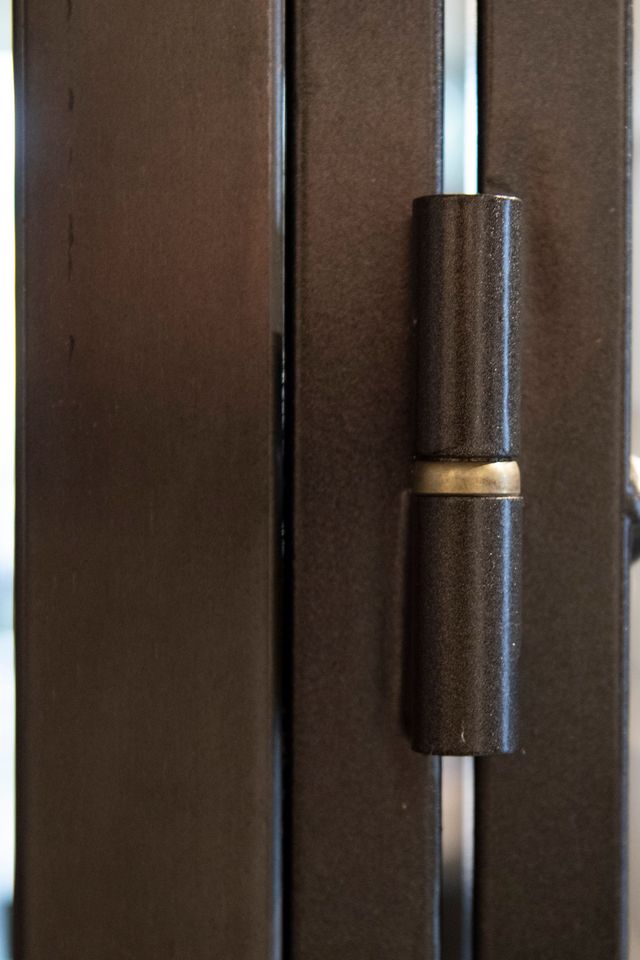 Primo piano di una cerniera per porta color bronzo, che ne mostra la forma cilindrica a botte.