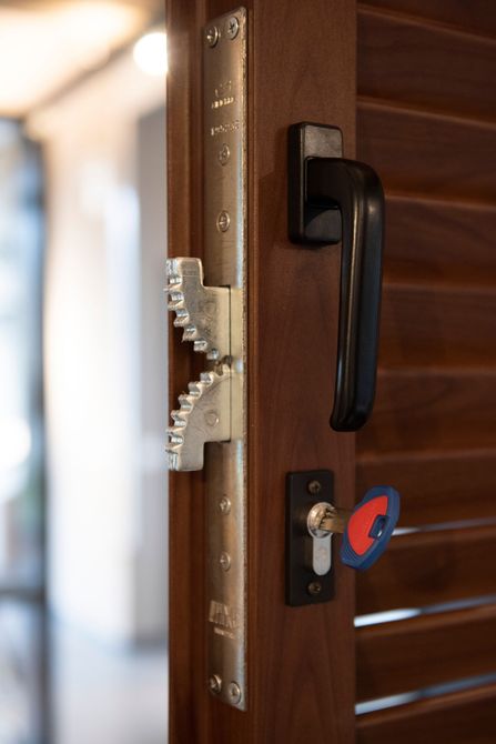 Primo piano di una porta di legno con un complesso meccanismo di chiusura, maniglia e chiave inserita.
