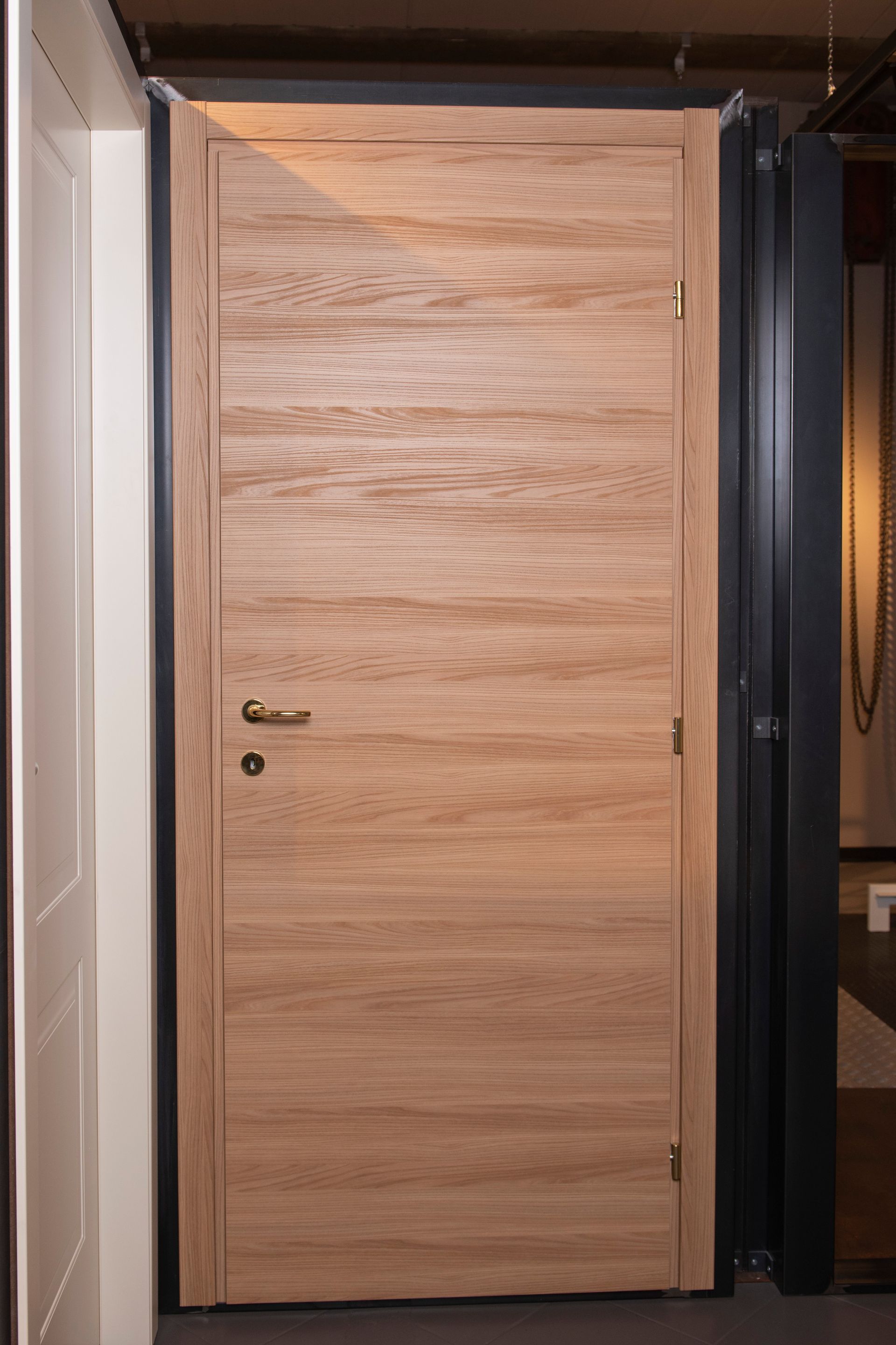 Porta interna in legno con venature orizzontali, ferramenta in metallo e colore marrone chiaro.