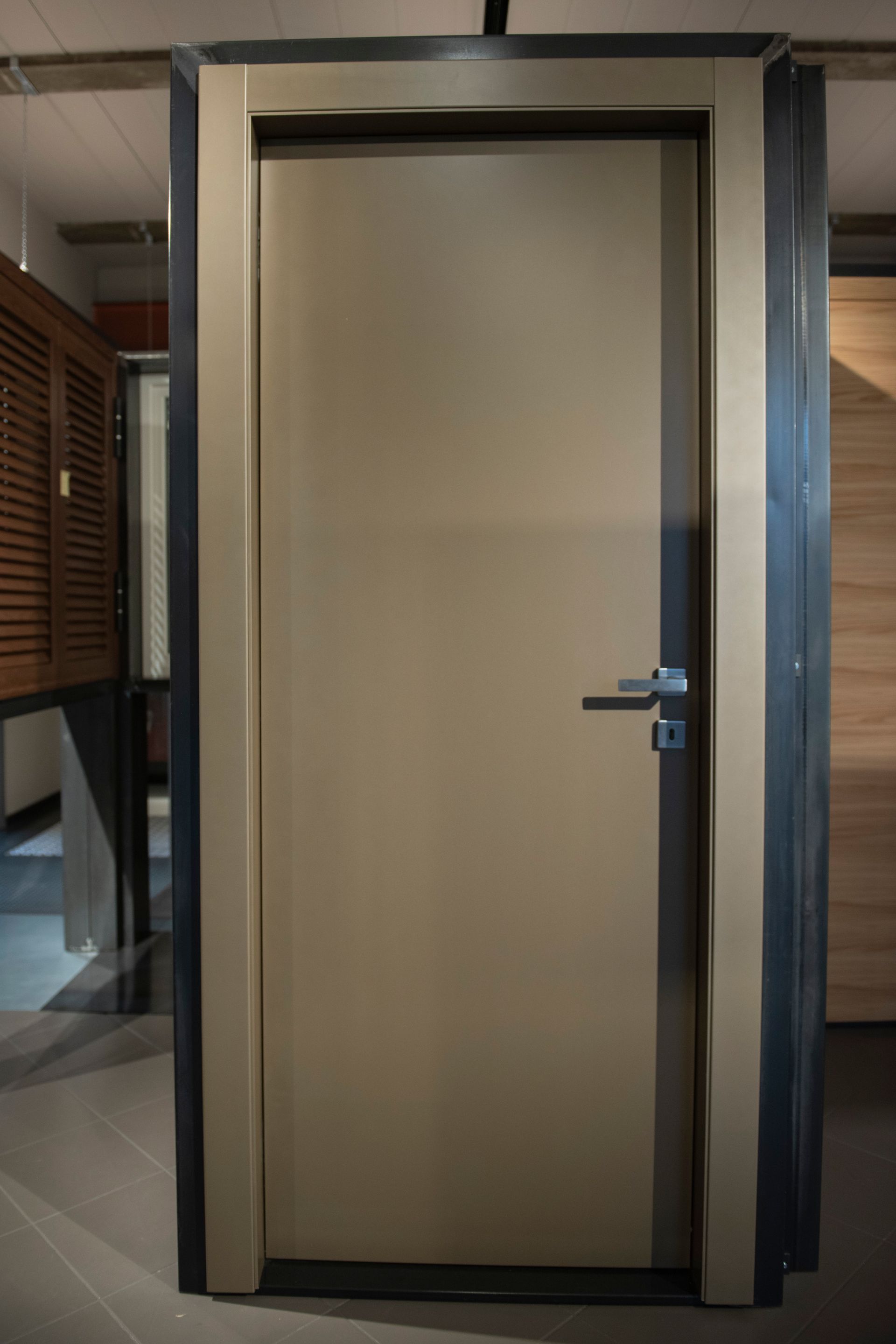 Porta interna color cuoio con finiture e maniglia grigio scuro, in uno showroom.