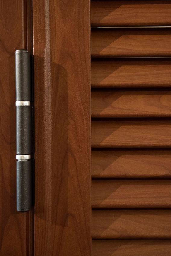 Anta di un mobile in legno marrone scuro con cerniera nera.
