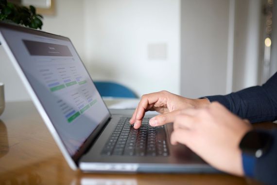 Persona che digita su un computer portatile con schermo visibile, mani sulla tastiera.
