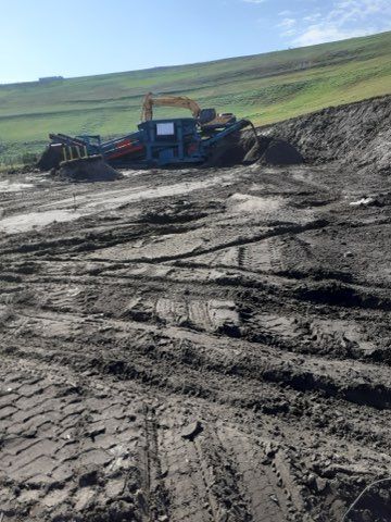 A large machine is sitting in the middle of a muddy field.